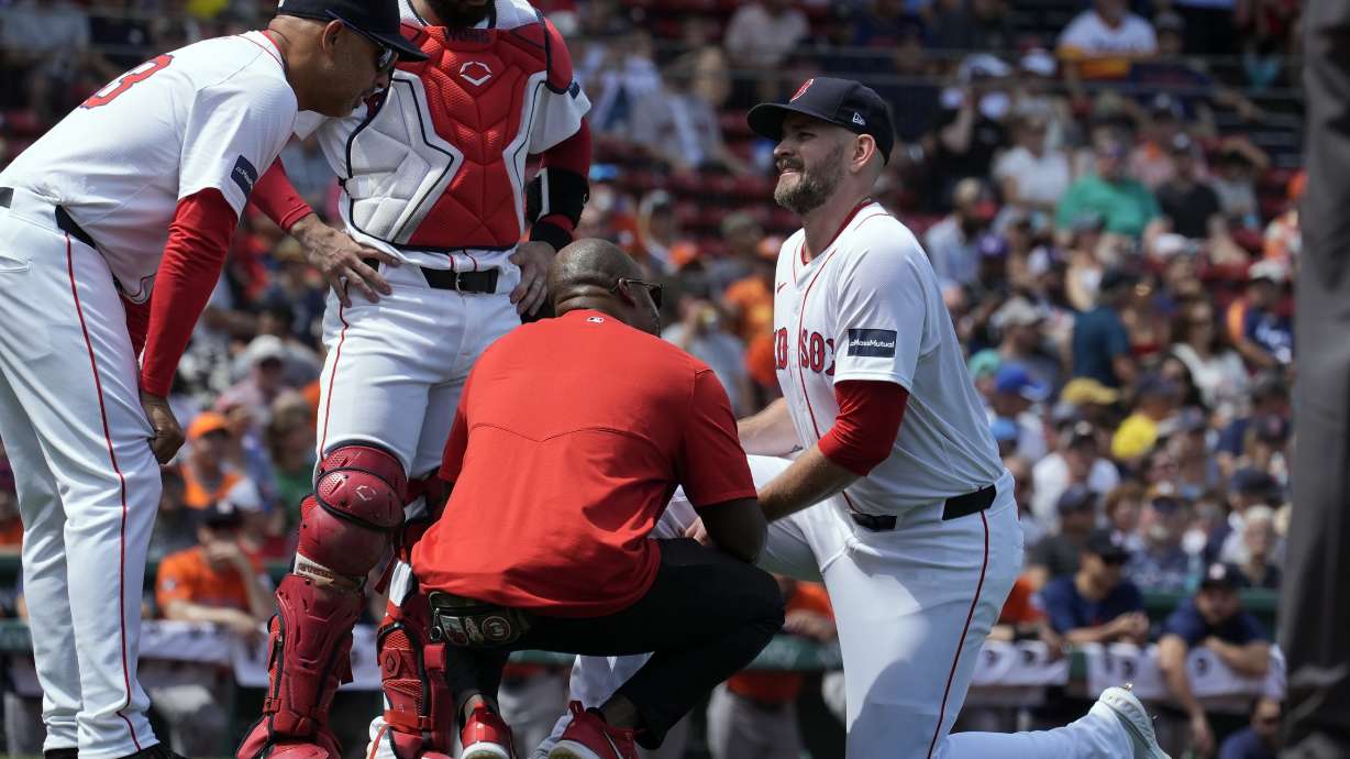 Boston Red Sox manager Alex Cora, left, and a trainer check on starting pitcher James Paxton, right, during the first inning of a baseball game against the Houston Astros, Sunday, Aug. 11, 2024, in Boston.
