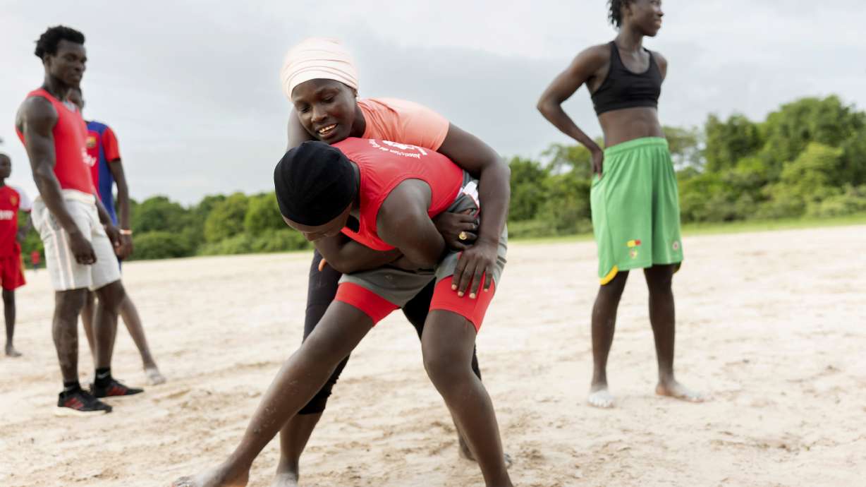 Coach Isabelle Sambou, 43 years old, rear, two-time Olympian and nine-time African wrestling champion, explains a move to a young woman during a wrestling training in Mlomp, southern Senegal, Wednesday, July 10, 2024.