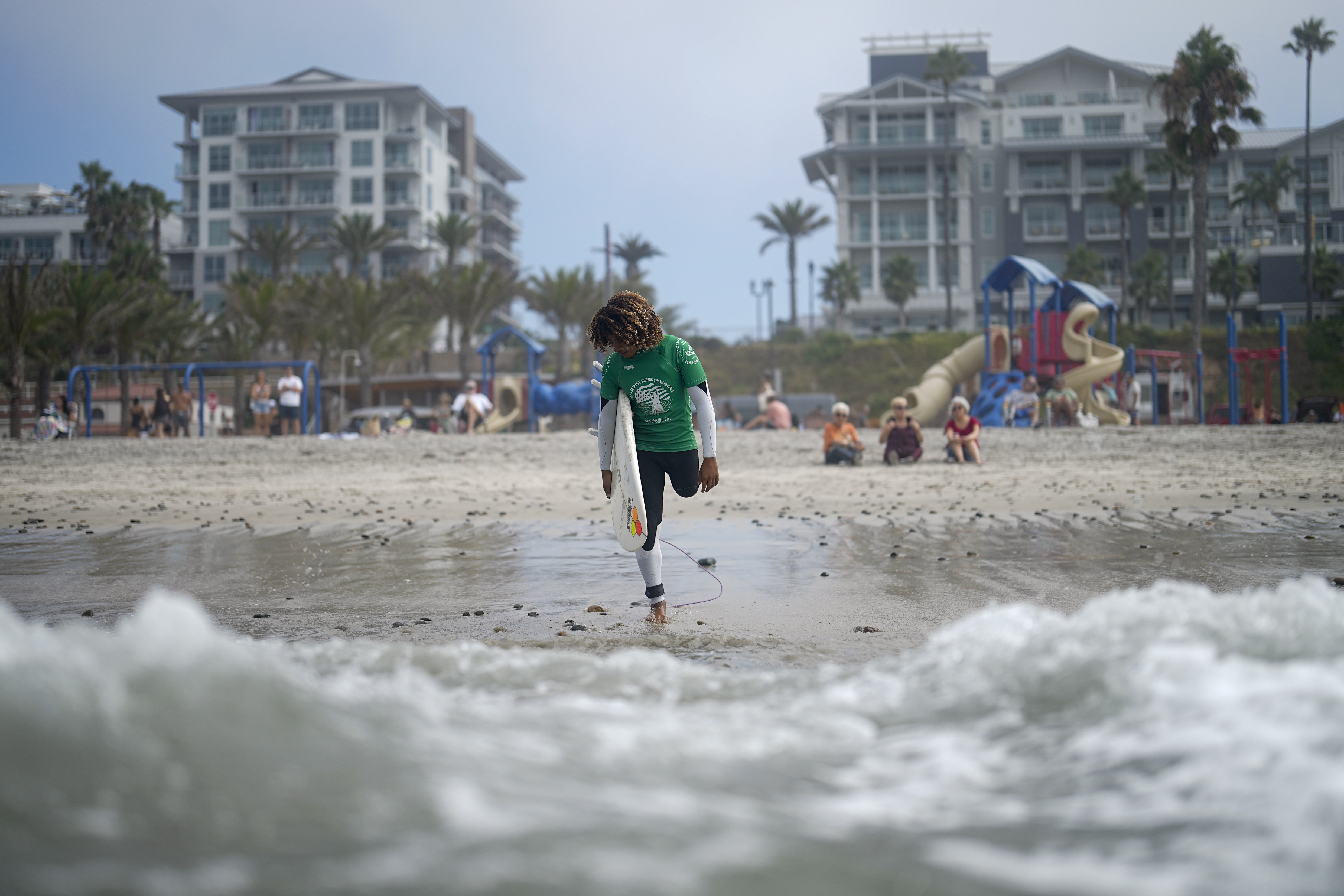 FILE - Dariel Melendez Davial, of Costa Rica, gets ready to enter the water during the U.S. Open Adaptive Surfing Championships, Sept. 8, 2023, in Oceanside, Calif.
