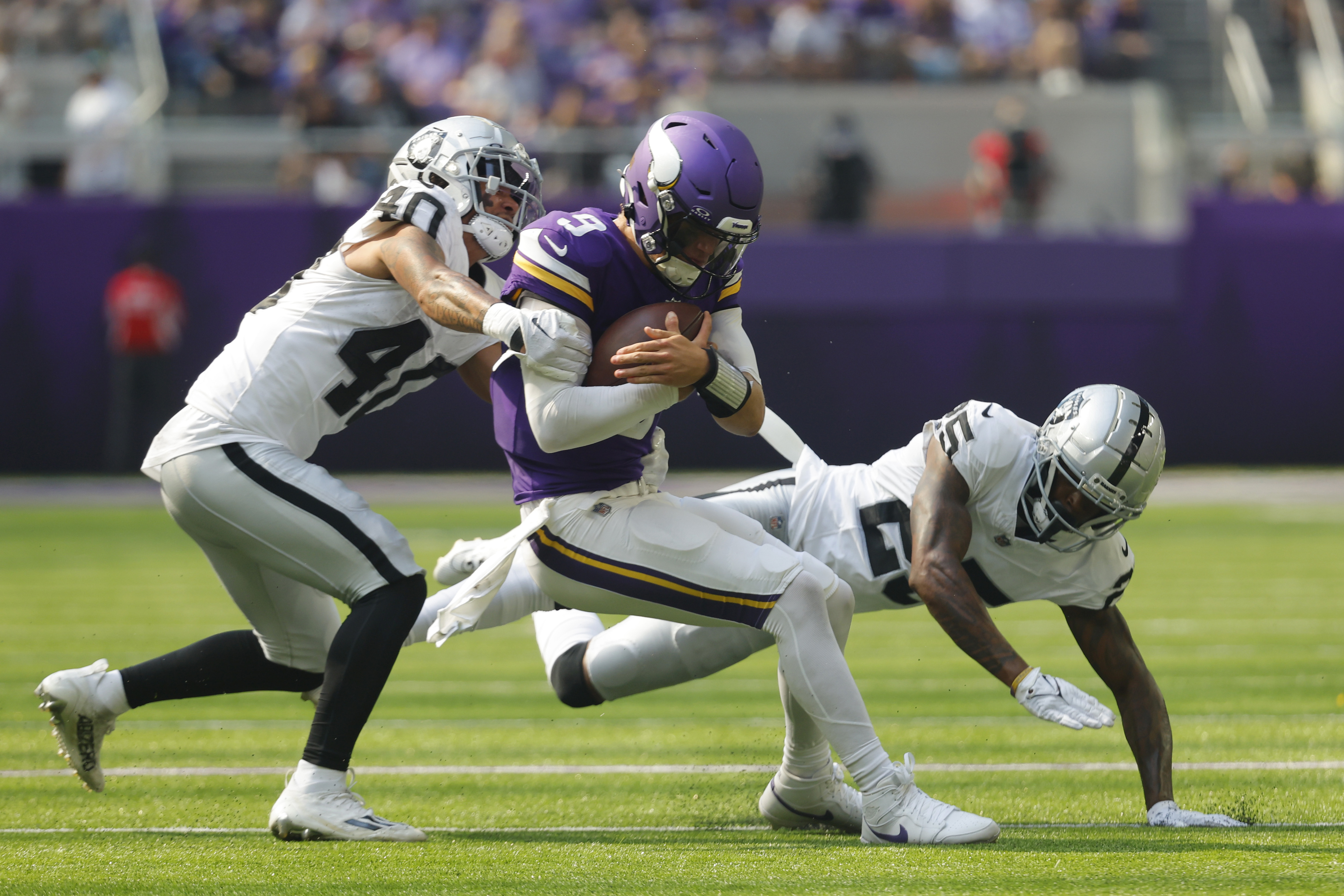 Minnesota Vikings quarterback J.J. McCarthy (9) is hit by Las Vegas Raiders safety Jaydon Grant (40) as he scramble for yards during the first half of an NFL football game Saturday, Aug. 10, 2024, in Minneapolis. 