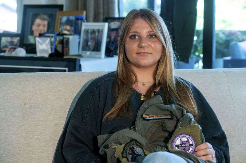 Gwyneth Collart sits for a portrait while holding the uniform of her brother Marine Cpl. Spencer R. Collart at her home, in Arlington, Va., June 19.