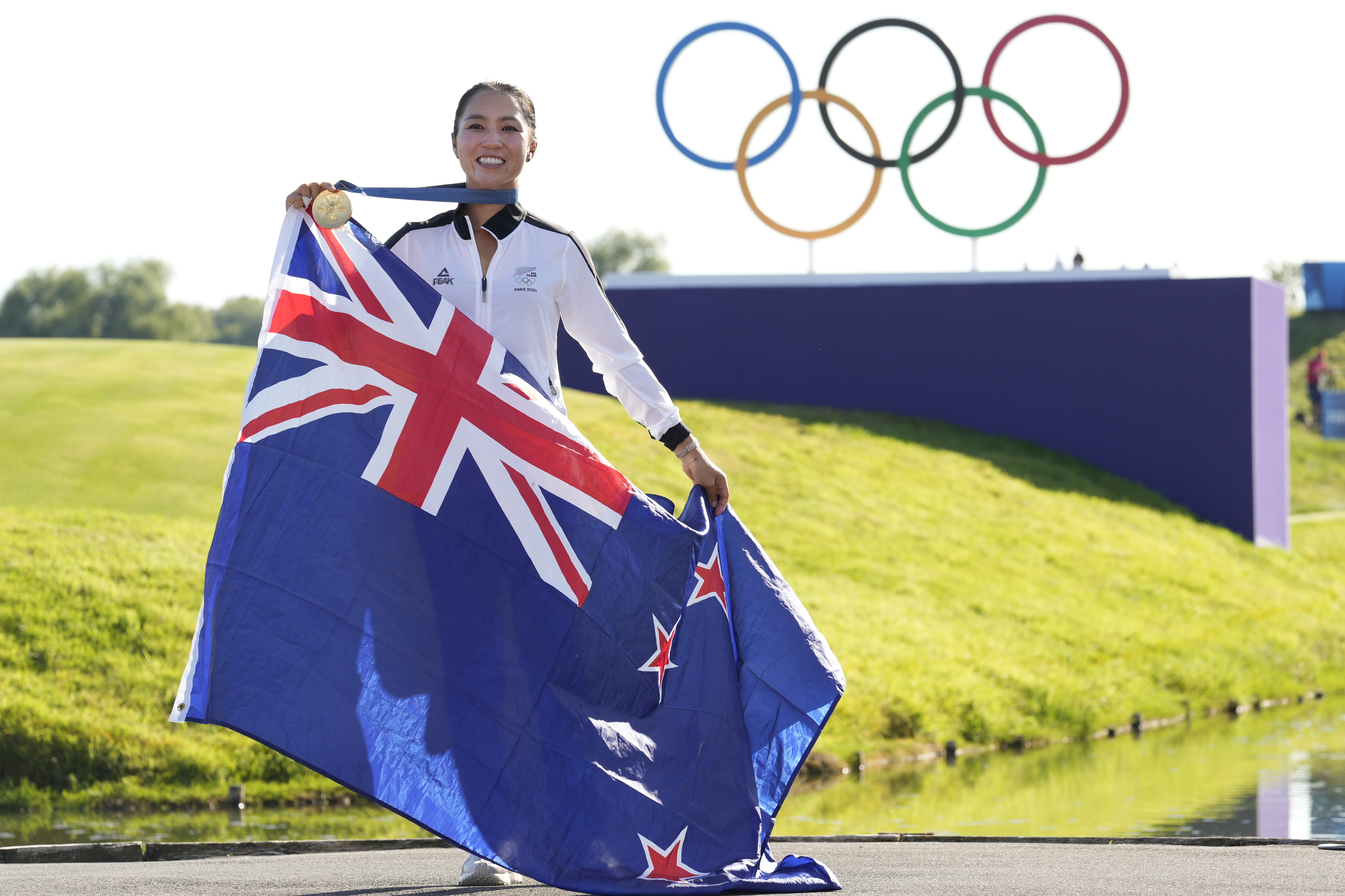 Lydia Ko, of New Zealand, poses for the cameras with her gold medal, and the New Zealand flag following final round of the women's golf event at the 2024 Summer Olympics, Saturday, Aug. 10, 2024, at Le Golf National, in Saint-Quentin-en-Yvelines, France. 