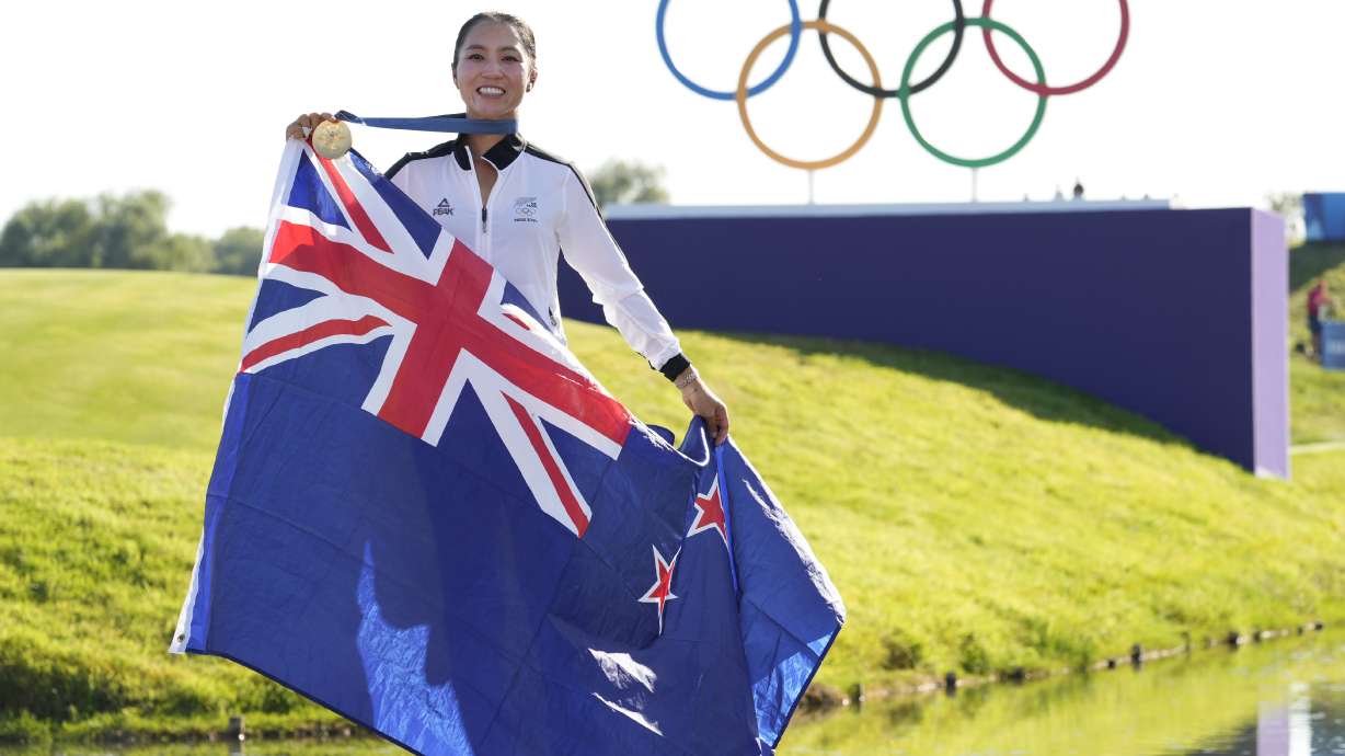 Lydia Ko, of New Zealand, poses for the cameras with her gold medal, and the New Zealand flag following final round of the women's golf event at the 2024 Summer Olympics, Saturday, Aug. 10, 2024, at Le Golf National, in Saint-Quentin-en-Yvelines, France.