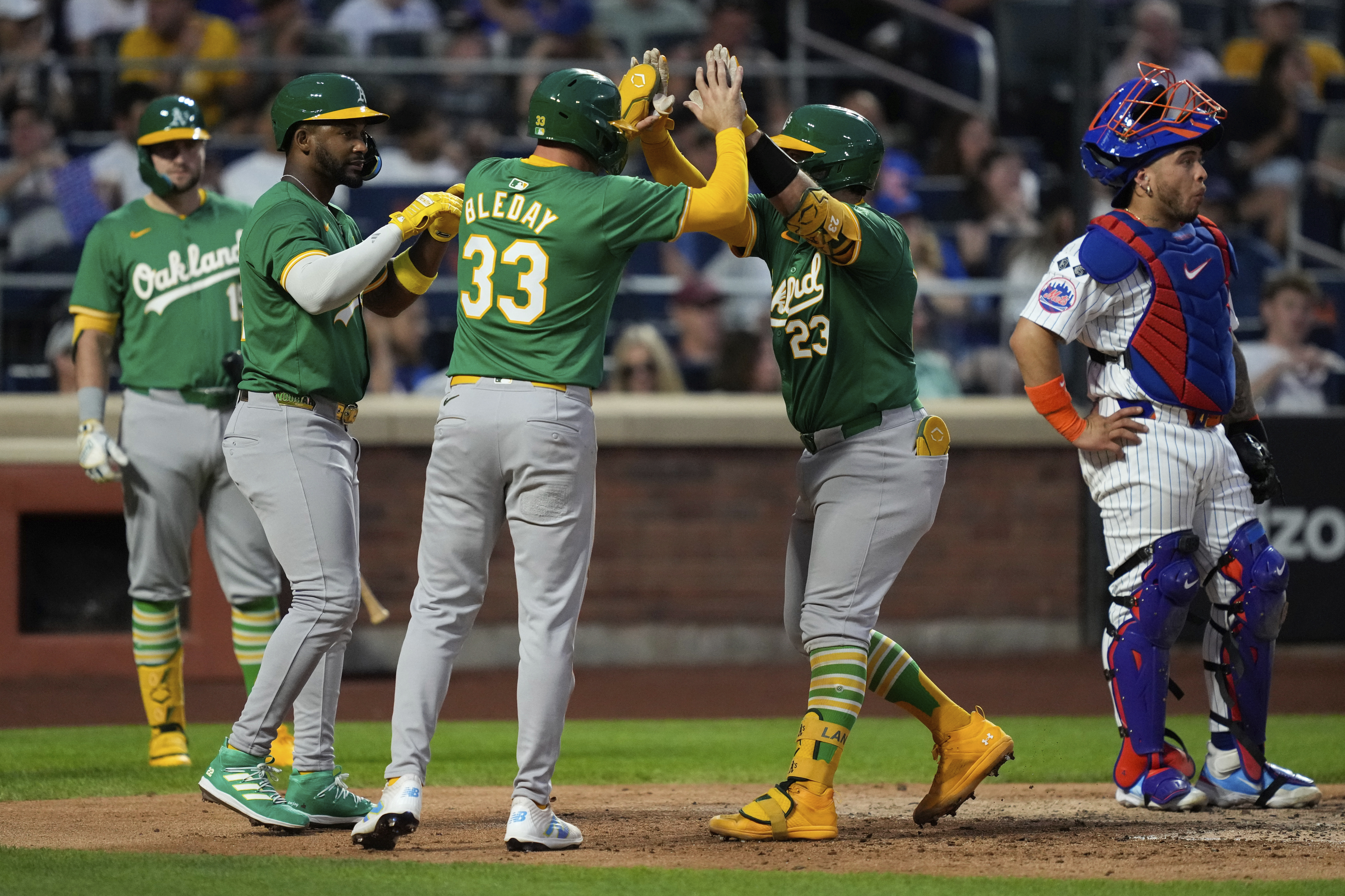 Oakland Athletics' Miguel Andujar, JJ Bleday (33) and Shea Langeliers (23) celebrate after Langeliers scores a three-run homerun during the third inning of a baseball game against the New York Mets, Tuesday, Aug. 13, 2024, in New York.