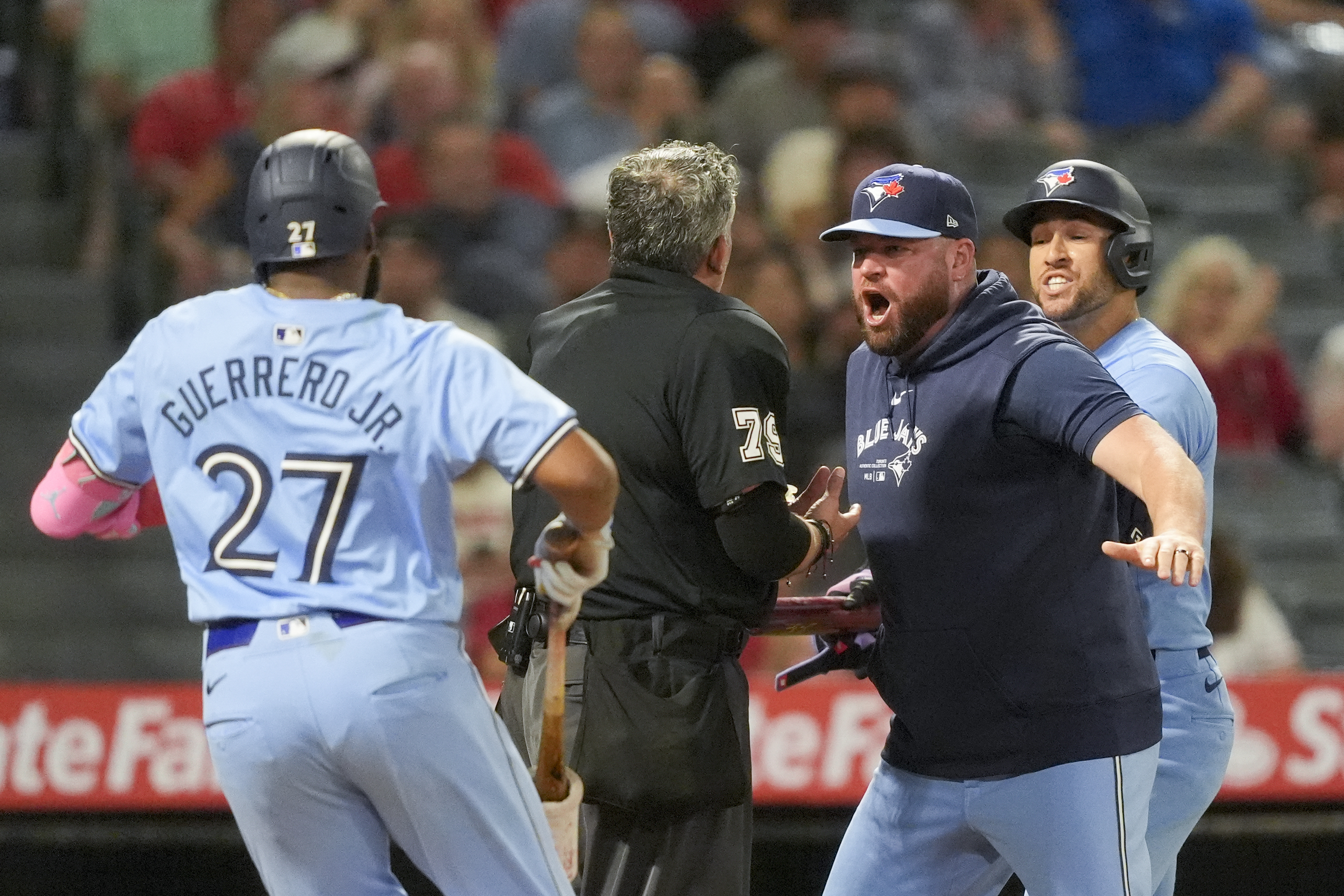 Home plate umpire Manny Gonzalez, center, argues with Toronto Blue Jays manager John Schneider, second from right, after throwing out George Springer, right, as Vladimir Guerrero Jr. runs over during the seventh inning of a baseball game against the Los Angeles Angels, Tuesday, Aug. 13, 2024, in Anaheim, Calif.