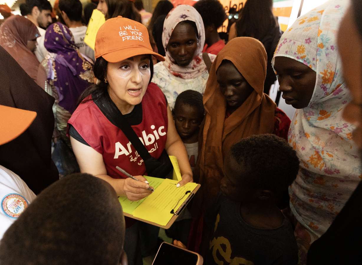Volunteer Marwa Najjar helps a family fill out the paperwork to get backpacks and school supplies for their children during Utah Refugee Connection’s annual back-to-school event at Granite Park Junior High School in South Salt Lake on Aug. 6.