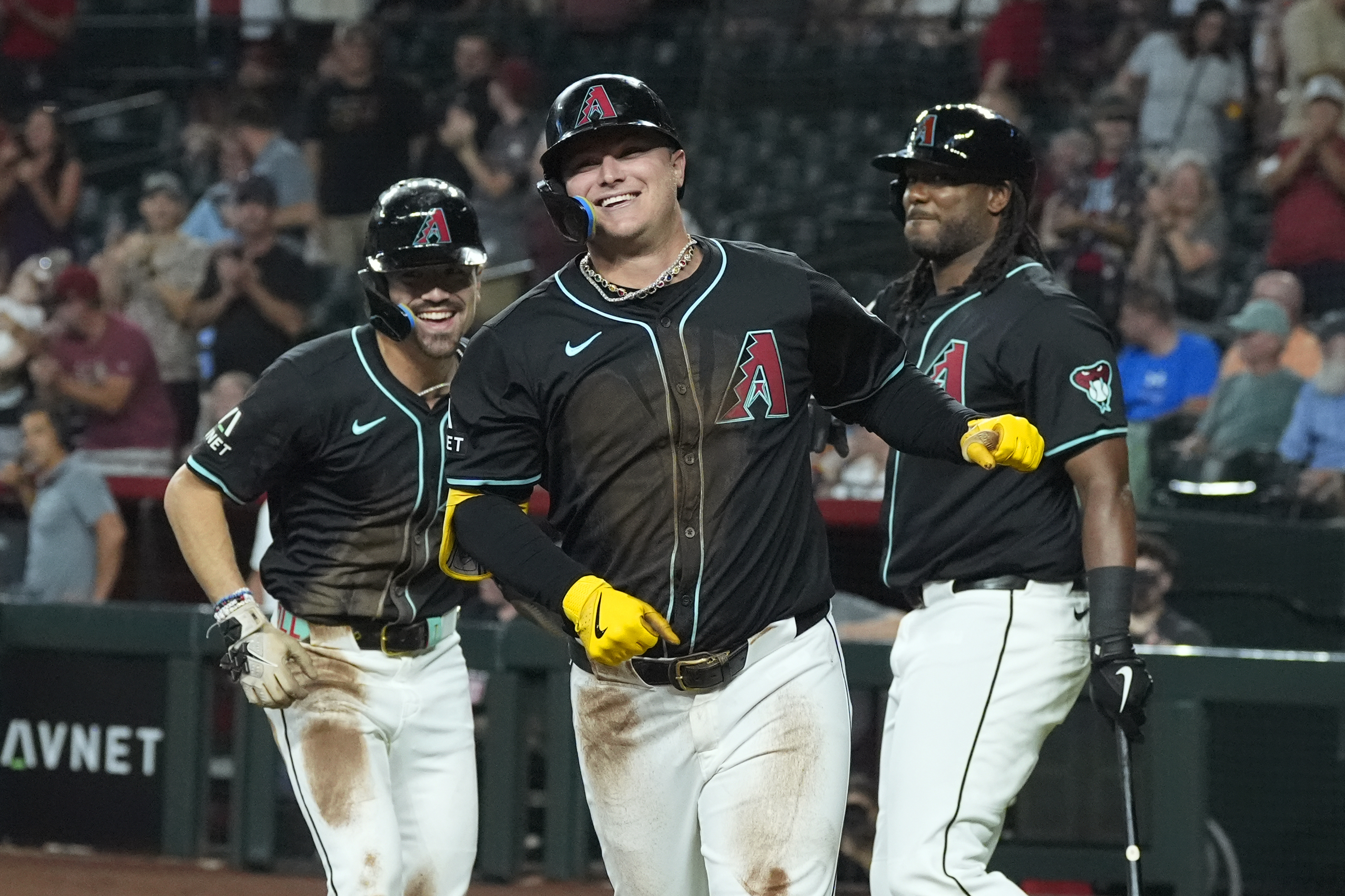 Arizona Diamondbacks' Joc Pederson, center, smiles as he celebrates with Corbin Carroll, left, and Josh Bell, right, after hitting a two-run double and scoring on a two-base error during the first inning of a baseball game, Wednesday, Aug. 14, 2024, in Phoenix.