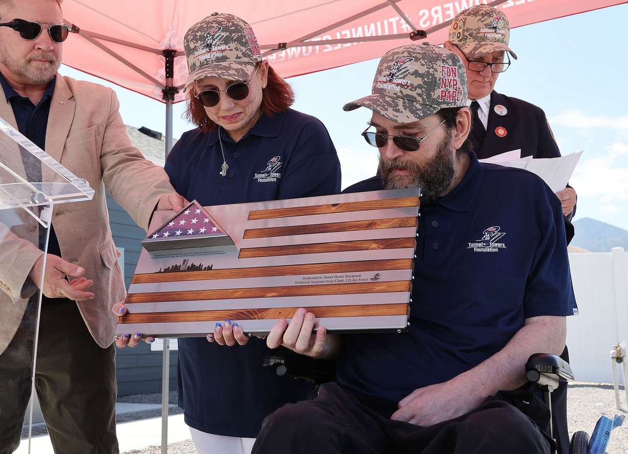 United States Air Force Technical Sgt. Jesse Clark and his wife Rebecca look over their flag artwork from 9/11 towers at their new, mortgage-free smart home from Tunnel to Towers Foundation in Tooele on Wednesday. Clark was diagnosed with a brain tumor linked to chemical exposure during the Gulf War.