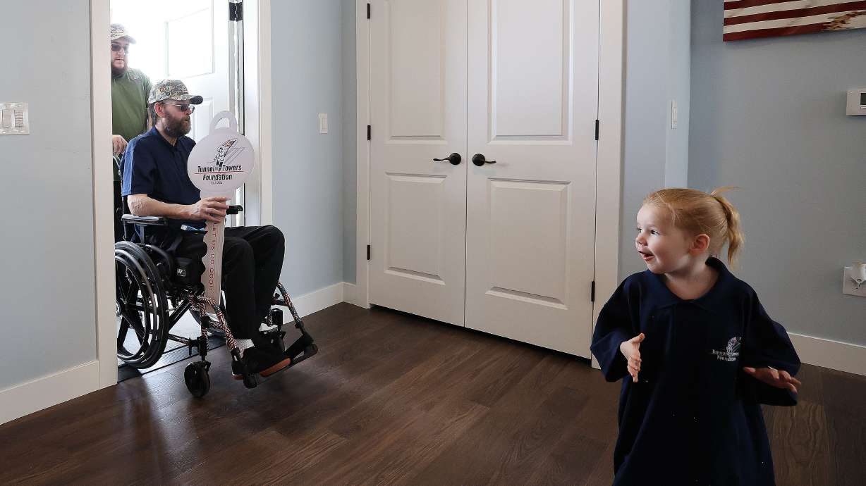 United States Air Force Technical Sgt. Jesse Clark and his granddaughter Austin Clark enter his new smart home from Tunnel to Towers Foundation in Tooele, Wednesday. Clark had a brain tumor linked to chemical exposure during the Gulf War.