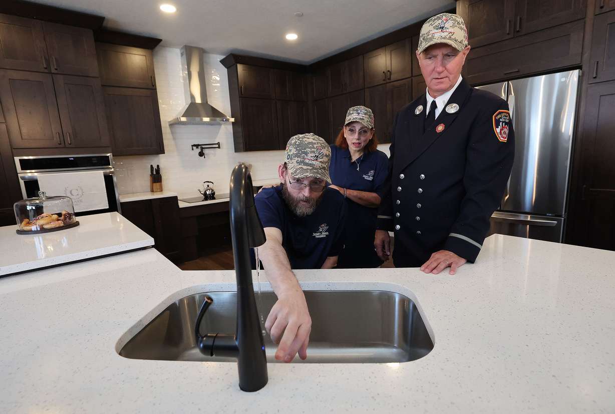 United States Air Force Technical Sgt. Jesse Clark and his wife, Rebecca, look over the touch kitchen faucet with Jack Kielty in their new, mortgage-free smart home from Tunnel to Towers Foundation in Tooele on Wednesday. Clark was diagnosed with a brain tumor linked to chemical exposure during the Gulf War.