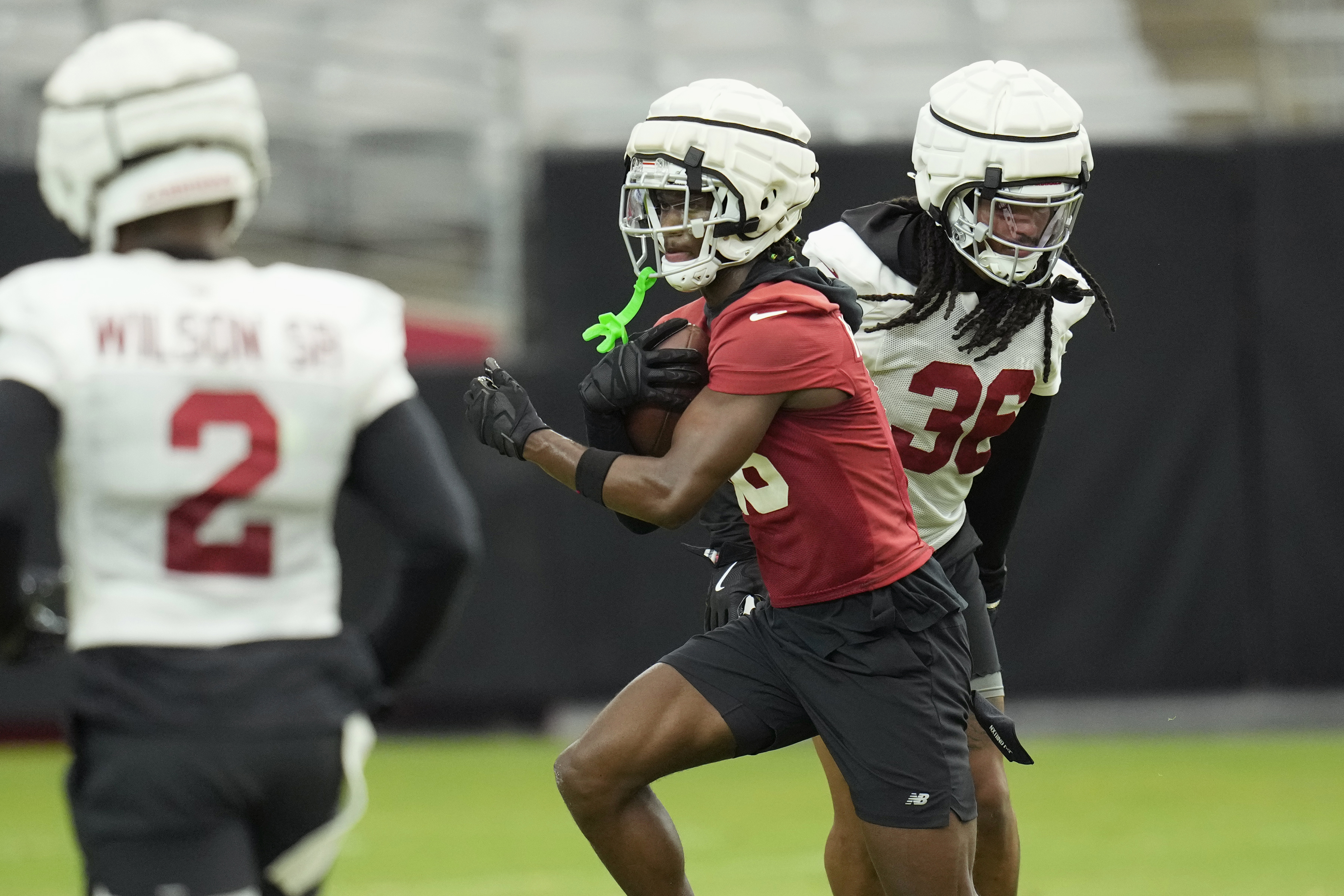 Arizona Cardinals wide receiver Marvin Harrison Jr., center, makes a catch between Cardinals linebacker Mack Wilson Sr. (2) and Cardinals safety Andre Chachere (36) as players take part in drills during an NFL football training camp at the State Farm Stadium Thursday, Aug. 1, 2024, in Glendale, Ariz. 