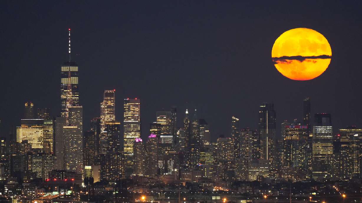 The moon rises through clouds over the skyline of lower Manhattan in this view from West Orange, N.J., Aug. 1, 2023, during a supermoon period. The first of four supermoons this year is about to rise.