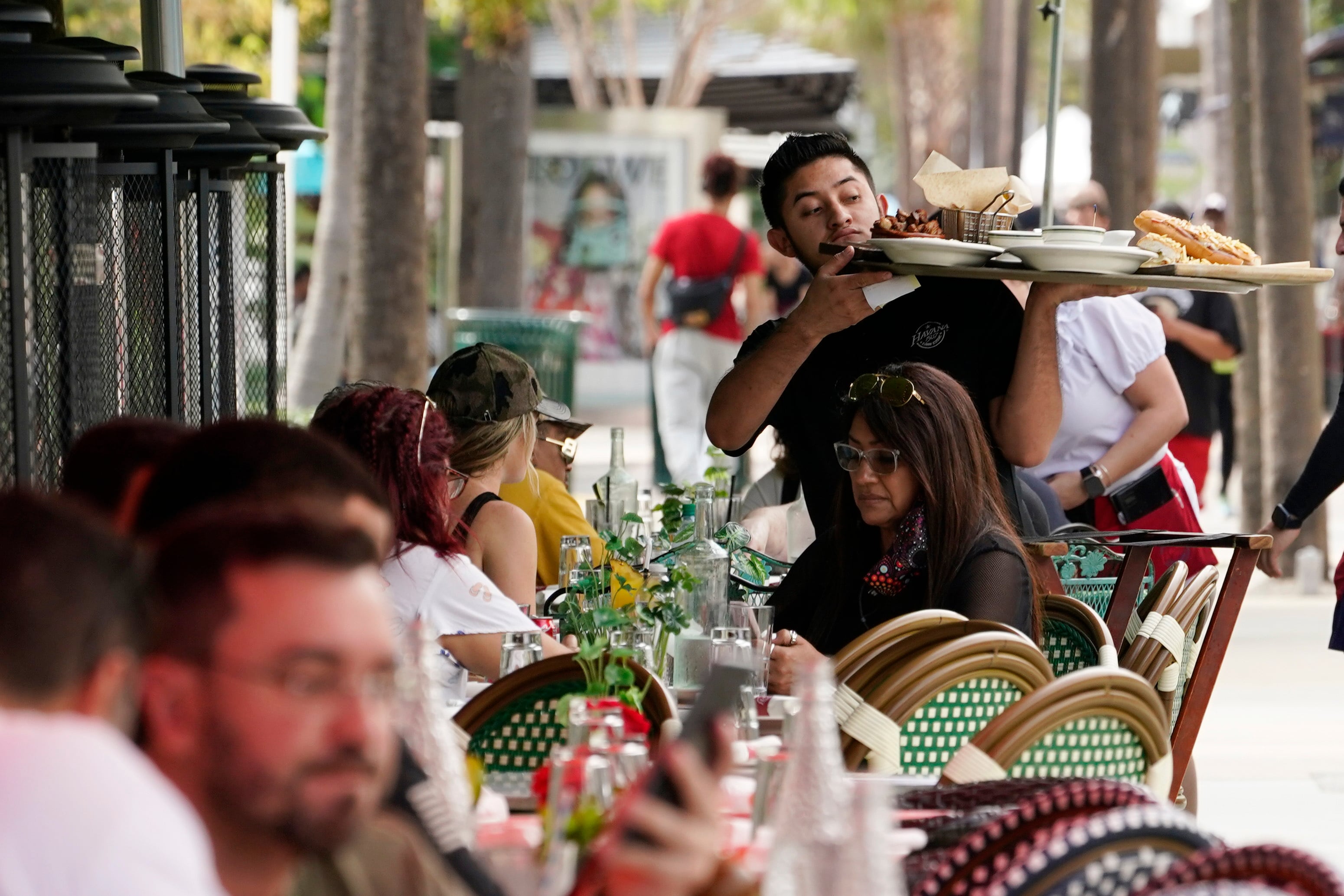 A waiter delivers food to patrons at a restaurant, Jan. 21, 2022, in Miami Beach, Fla. Vice President Kamala Harris and former President Donald Trump found common ground recently when they both supported slashing taxes on tips.