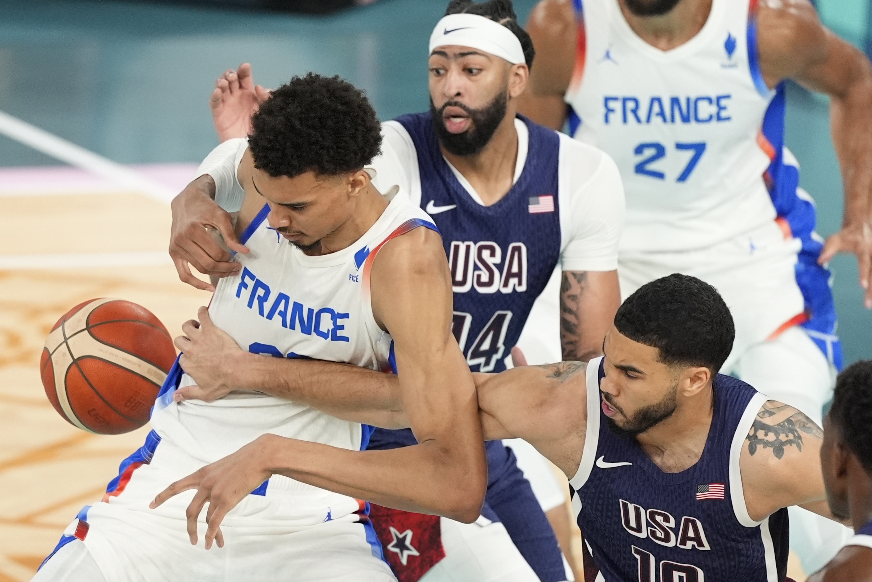 United States' Jayson Tatum (10) knocks the ball from Victor Wembanyama (32), of France during a men's gold medal basketball game at Bercy Arena at the 2024 Summer Olympics, Saturday, Aug. 10, 2024, in Paris, France. 