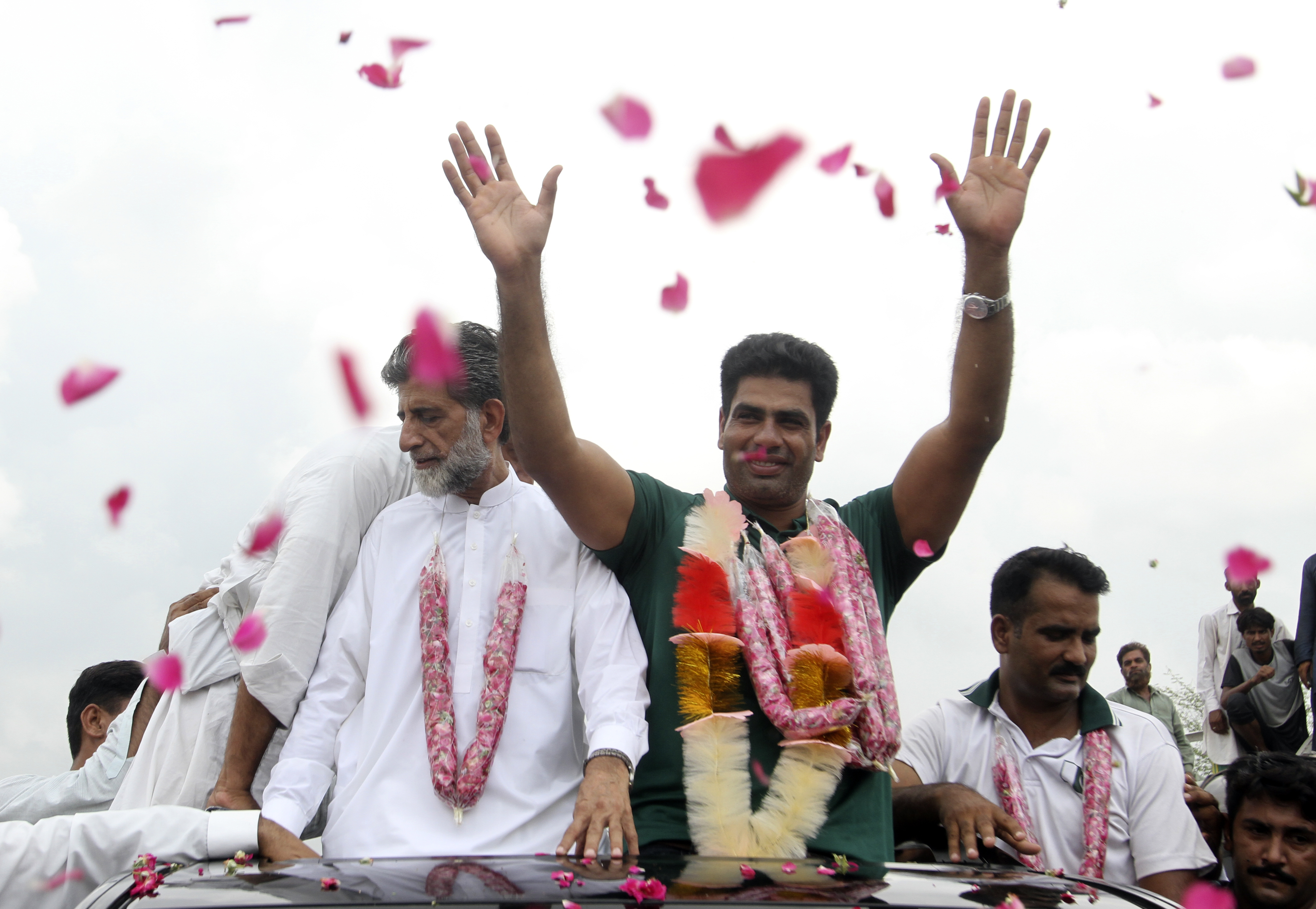 Men's javelin gold medalist, Arshad Nadeem of Pakistan, centre, waves to people outside his village in Mian Channu, Khanewal district, of Pakistan, Sunday, Aug. 11, 2024. 