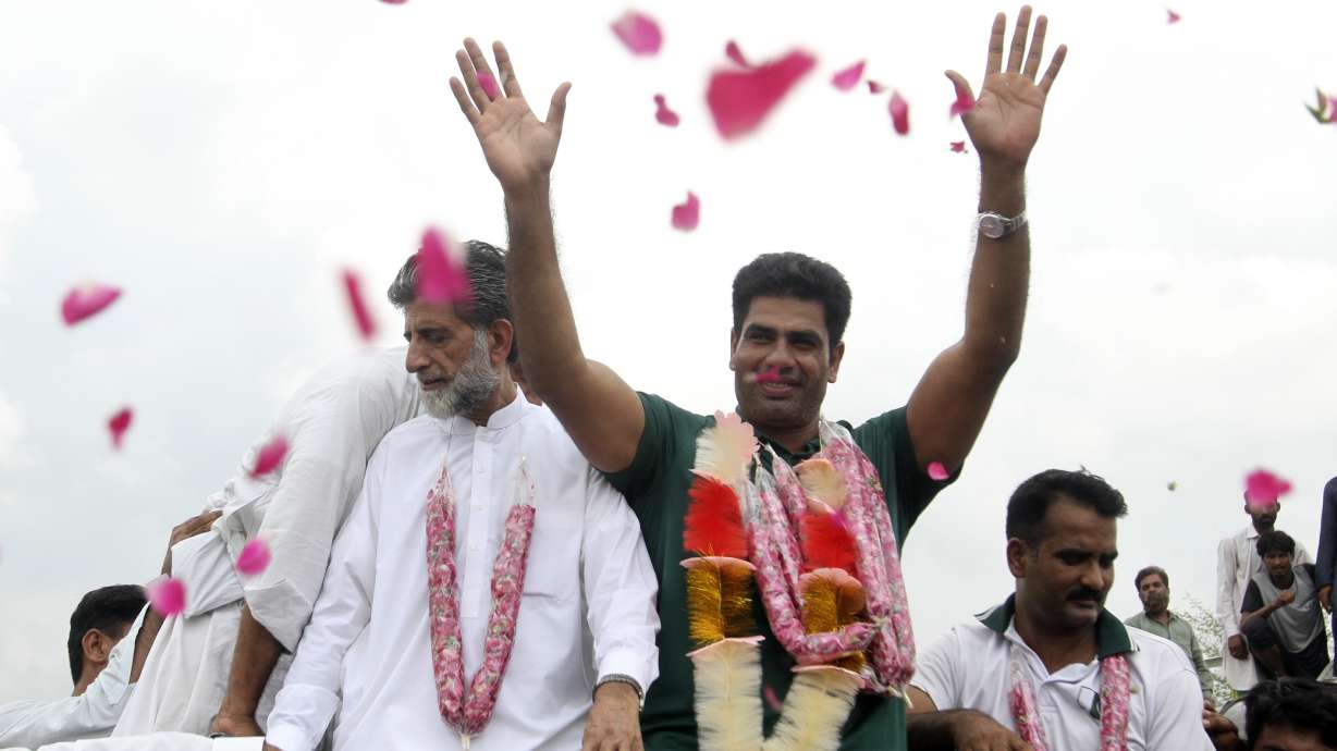 Men's javelin gold medalist, Arshad Nadeem of Pakistan, centre, waves to people outside his village in Mian Channu, Khanewal district, of Pakistan, Sunday, Aug. 11, 2024.