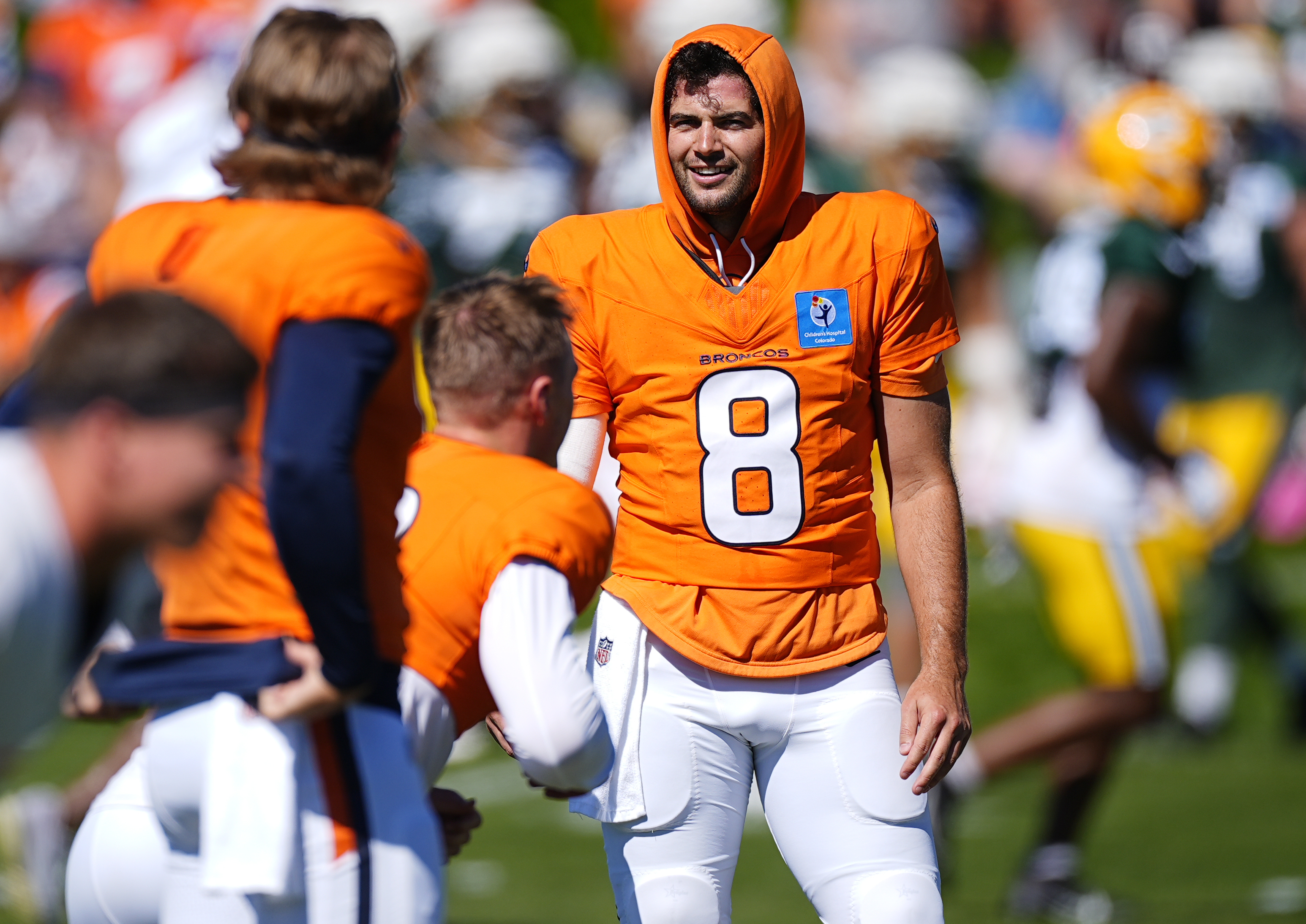 Denver Broncos quarterback Jarrett Stidham (8) jokes with fellow quarterbacks Bo Nix, center, and Zach Wilson as they warm up before a joint NFL training camp practice with the Green Bay Packers at the Broncos' headquarters Friday, Aug. 16, 2024, in Centennial, Colo. 