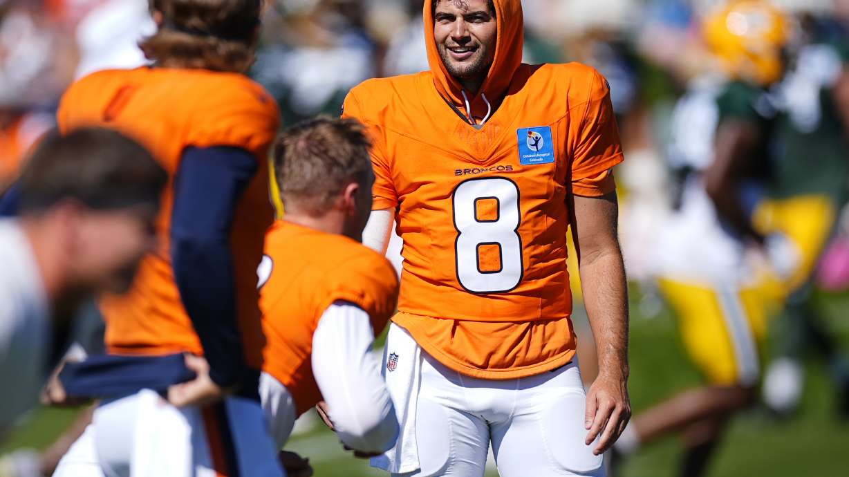Denver Broncos quarterback Jarrett Stidham (8) jokes with fellow quarterbacks Bo Nix, center, and Zach Wilson as they warm up before a joint NFL training camp practice with the Green Bay Packers at the Broncos' headquarters Friday, Aug. 16, 2024, in Centennial, Colo.