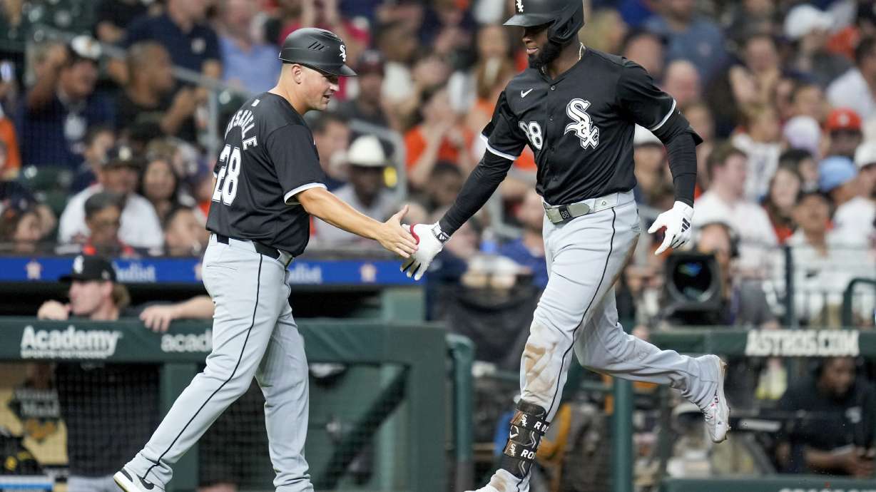 Chicago White Sox's Luis Robert Jr., right, celebrates after his two-run home run against the Houston Astros with third base coach Justin Jirschele, left, during the third inning of a baseball game Friday, Aug. 16, 2024, in Houston.