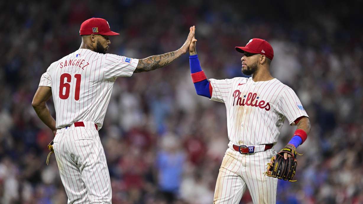 Philadelphia Phillies' Cristopher Sánchez (61) high-fives Edmundo Sosa after Sosa completing a double play against the Washington Nationals during the eighth inning of a baseball game, Saturday, Aug. 17, 2024, in Philadelphia.