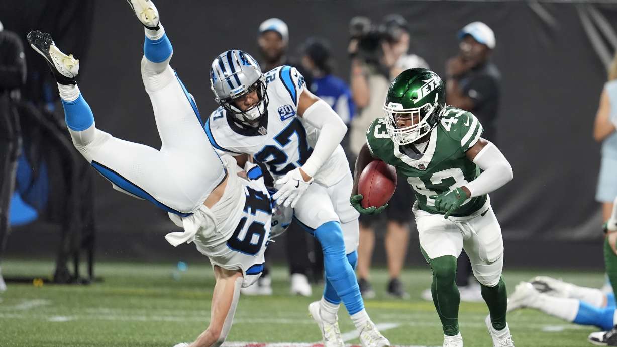 New York Jets' Brandon Codrington (43) returns a punt against Carolina Panthers' Feleipe Franks (49) and Alex Cook (27) during the second half of a preseason NFL football game, Saturday, Aug. 17, 2024, in Charlotte, N.C.