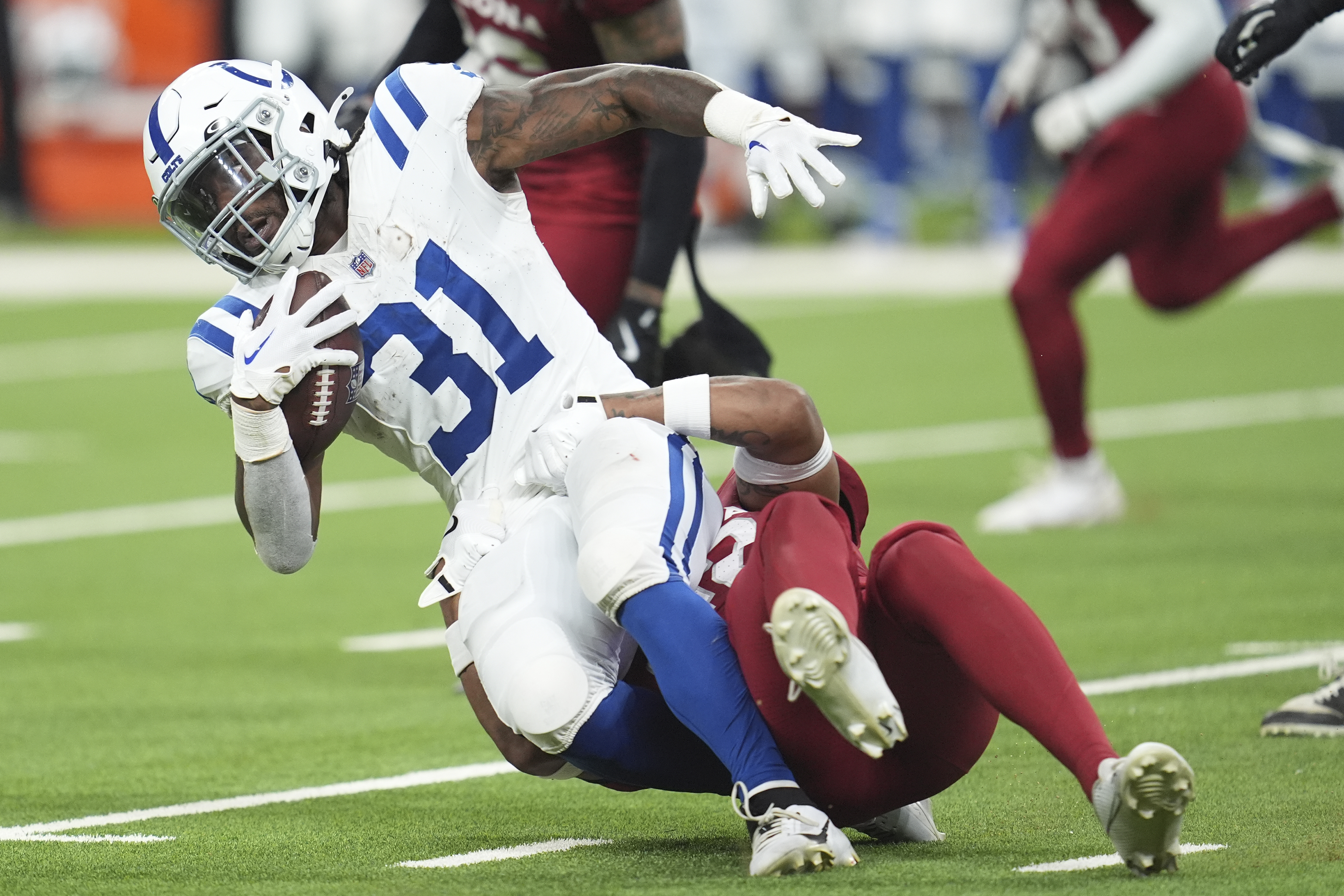 Indianapolis Colts running back Tyler Goodson (31) gets pulled down by Arizona Cardinals safety Dadrion Taylor-Demerson during the first half of a preseason NFL football game, Saturday, Aug. 17, 2024, in Indianapolis. 