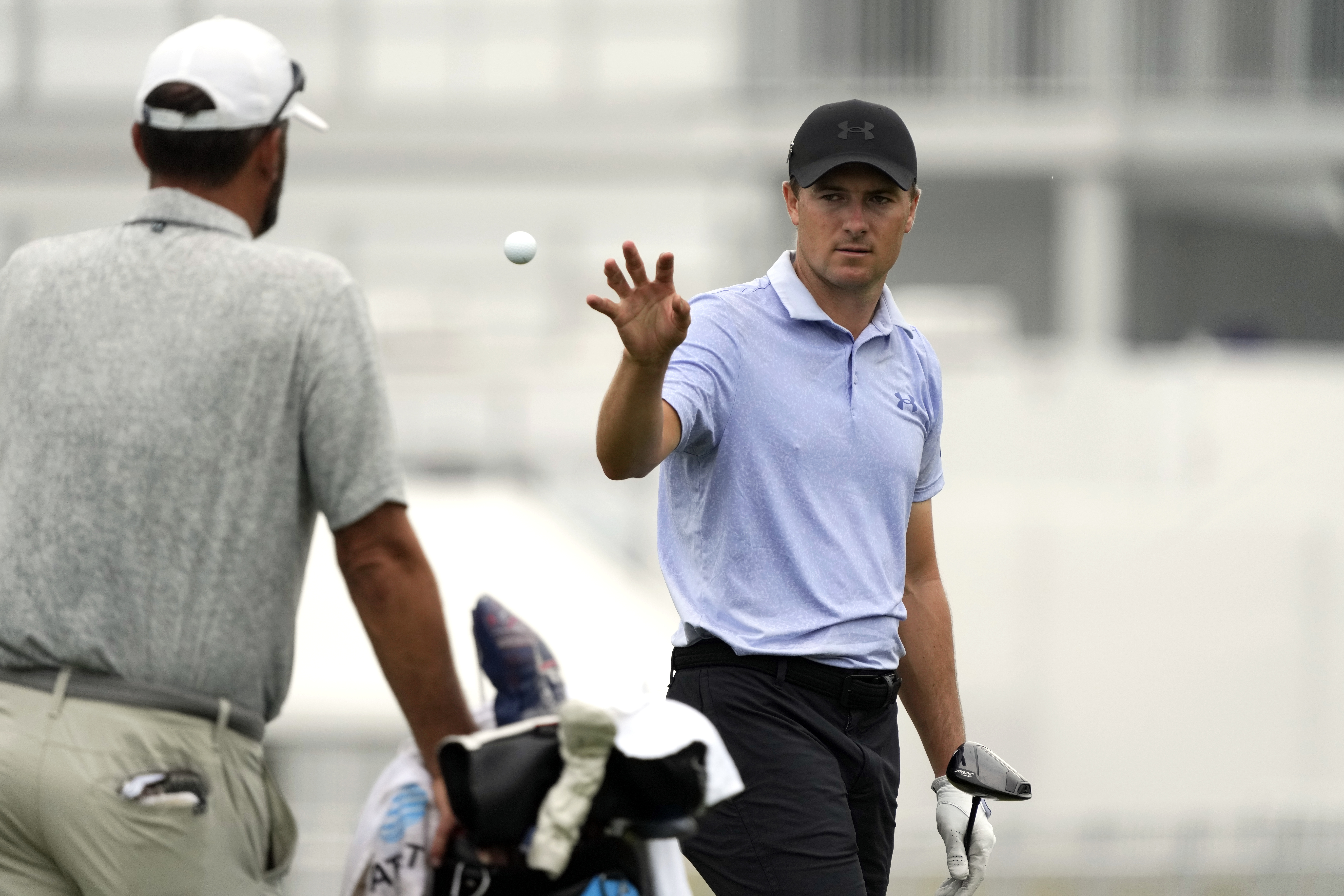 Jordan Spieth, right, catches a ball tossed to him on the driving range at the St. Jude Championship golf tournament Wednesday, Aug. 14, 2024, in Memphis, Tenn. The tournament is scheduled to begin Thursday.