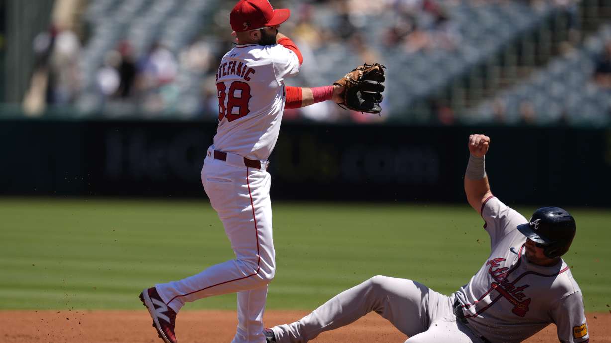 Los Angeles Angels second baseman Michael Stefanic, left, throws out Atlanta Braves designated hitter Marcell Ozuna at first base to complete a double play after forcing out Austin Riley, right, during the first inning of a baseball game, Sunday, Aug. 18, 2024, in Anaheim, Calif.