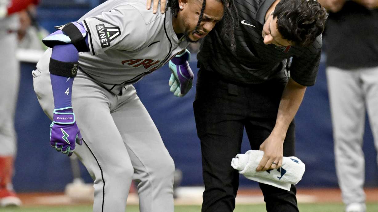 Arizona Diamondbacks Ketel Marte, left, is helped after being injured while batting during the 10th inning of a baseball game against the Tampa Bay Rays, Sunday, Aug. 18, 2024, in St. Petersburg, Fla.