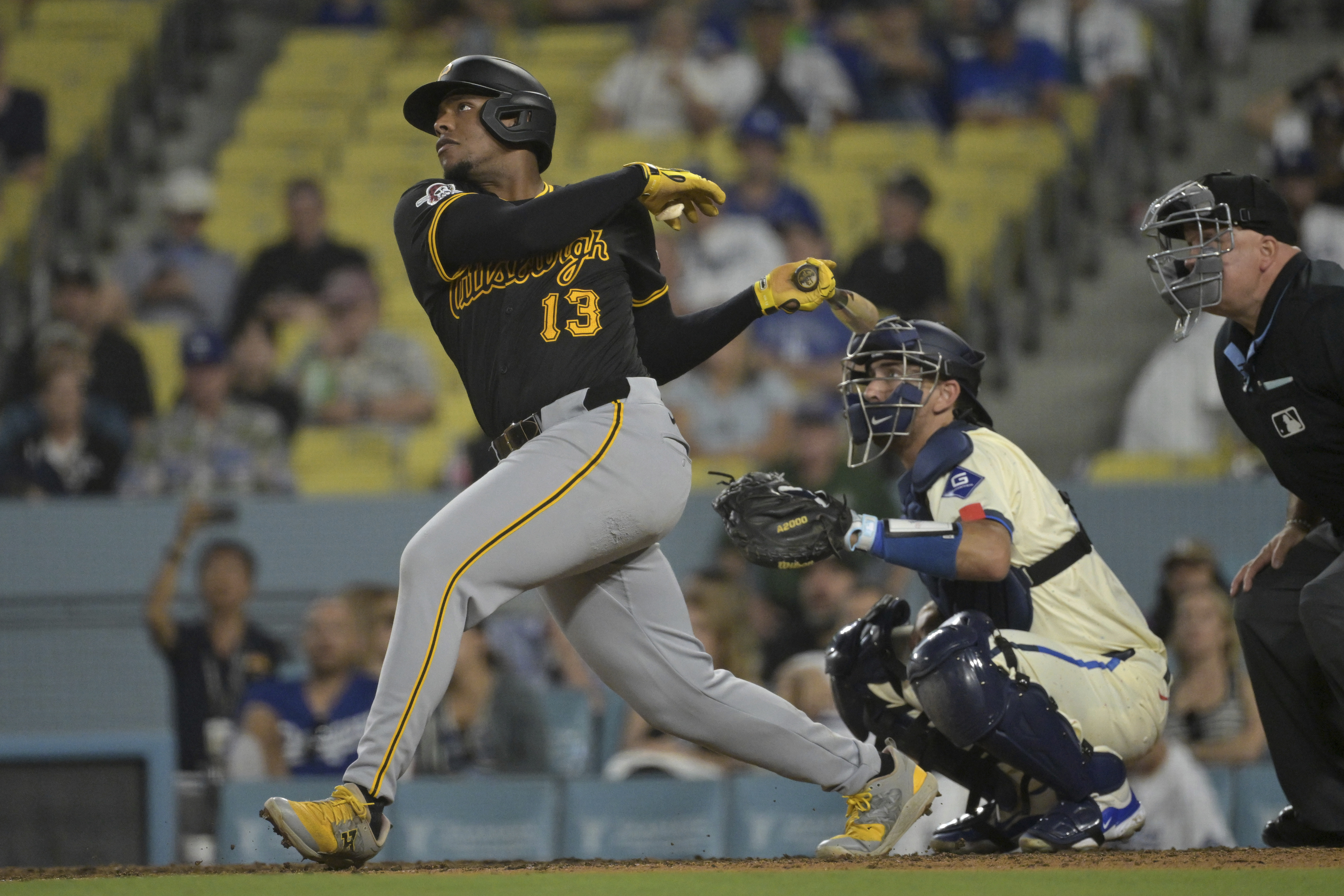 Pittsburgh Pirates' Ke'Bryan Hayes (13) hits a solo home run as Los Angeles Dodgers' Austin Barnes looks on from behind the plate in the ninth inning of a baseball game on Saturday, Aug. 10, 2024, in Los Angeles. 