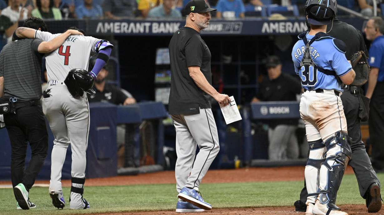 Arizona Diamondbacks manager Torey Lovullo, center, makes a substitution as Diamondbacks' Ketel Marte (4) is helped off the field after being injured while batting during the 10th inning of a baseball game against the Tampa Bay Rays, Sunday, Aug. 18, 2024, in St. Petersburg, Fla.