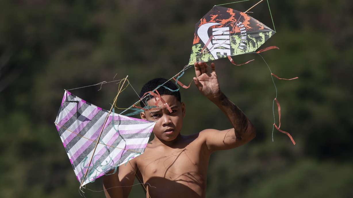 A youth holds kites during a festival in the Turano favela in Rio de Janeiro, Sunday, July 7, 2024.