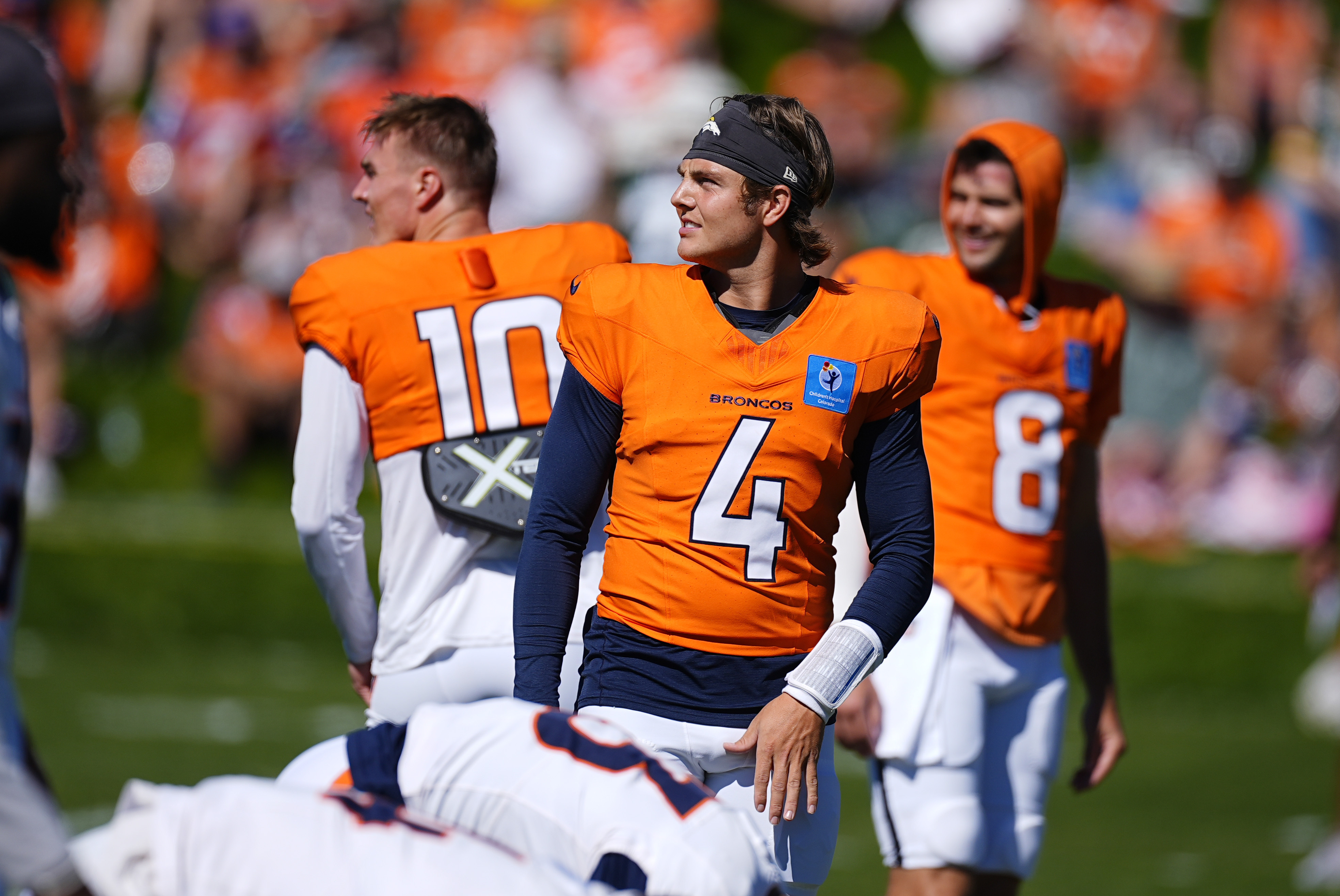 Denver Broncos quarterbacks Zach Wilson (4), Bo Nix (10) and Jarrett Stidham (8) stretch before a joint NFL football practice with the Green Bay Packers at the Broncos' headquarters Friday, Aug. 16, 2024, in Centennial, Colo.