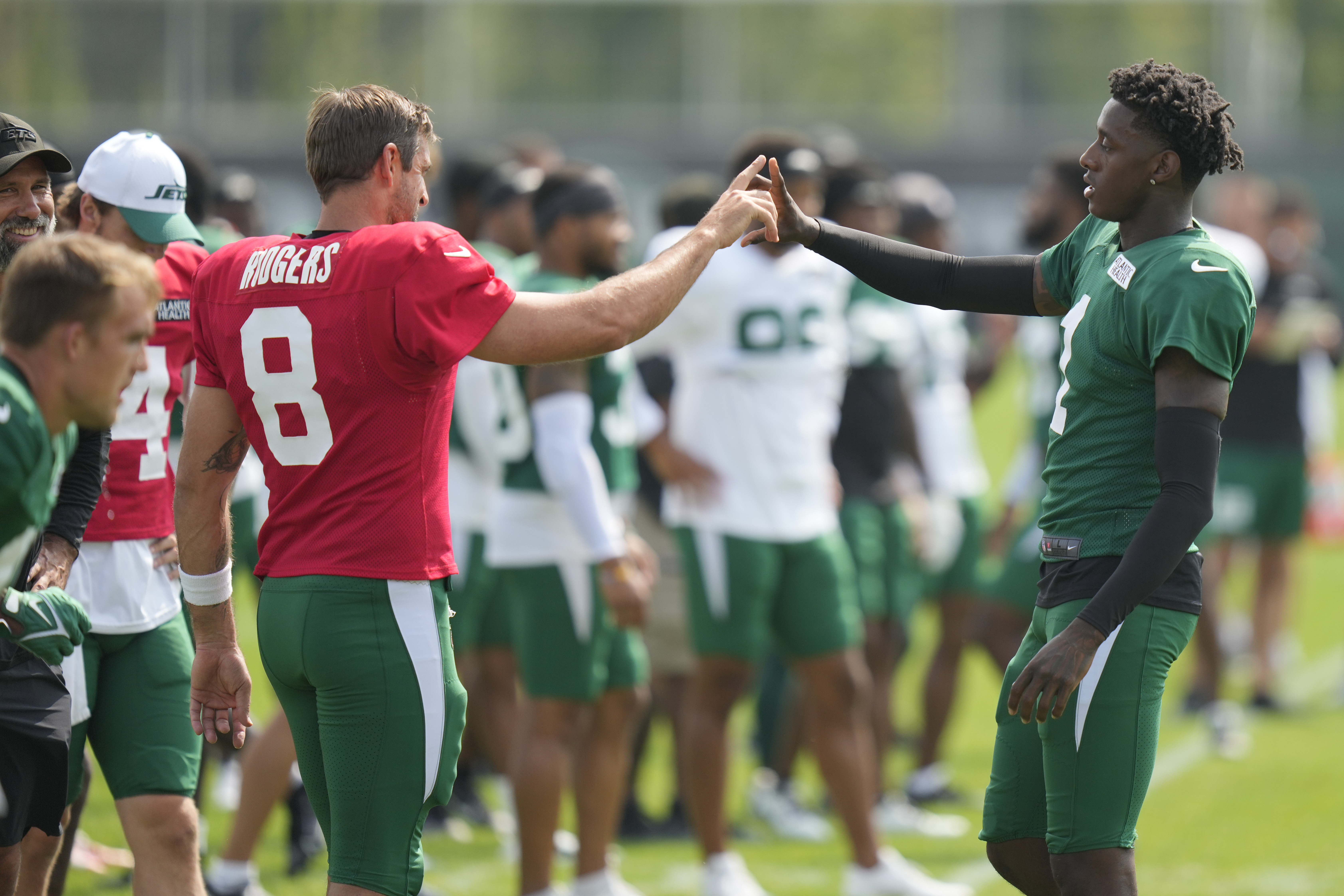 New York Jets' Sauce Gardner, right, greets quarterback Aaron Rodgers (8) during practice at the NFL football team's training facility in Florham Park, N.J., Tuesday, July 30, 2024. 