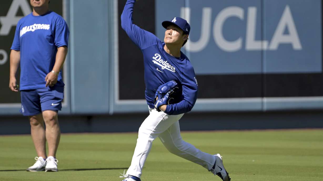 Los Angeles Dodgers starting pitcher Yoshinobu Yamamoto, right, throws in the outfield as interpreter Yoshihiro Sonoda, left, looks on prior to a baseball game against the Pittsburgh Pirates, Saturday, Aug. 10, 2024, in Los Angeles.