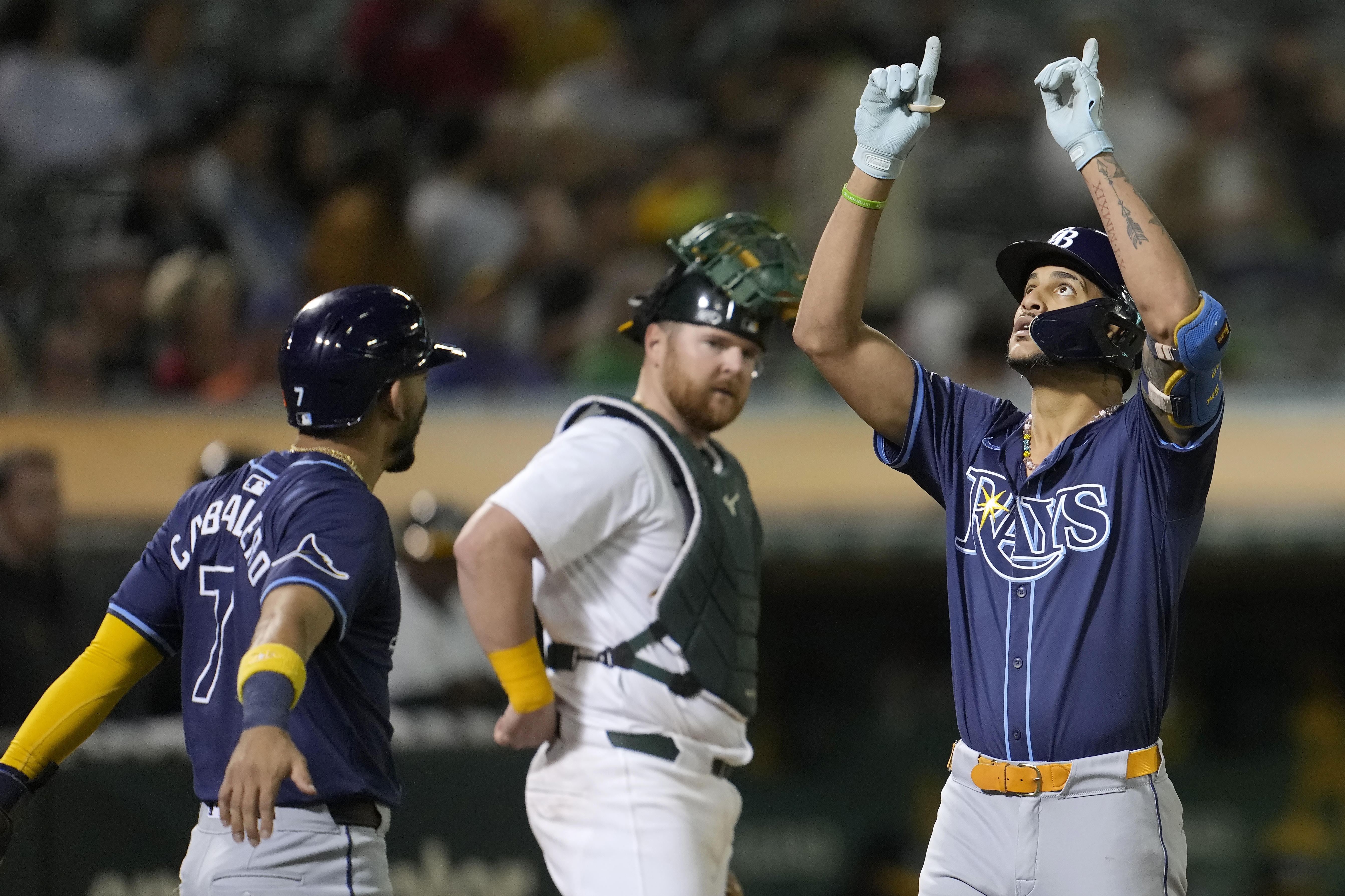 Tampa Bay Rays' Jose Siri, right, celebrates after hitting a two-run home run that also scored José Caballero, left, as Oakland Athletics catcher Kyle McCann, middle, reacts during the seventh inning of a baseball game in Oakland, Calif., Wednesday, Aug. 21, 2024. 