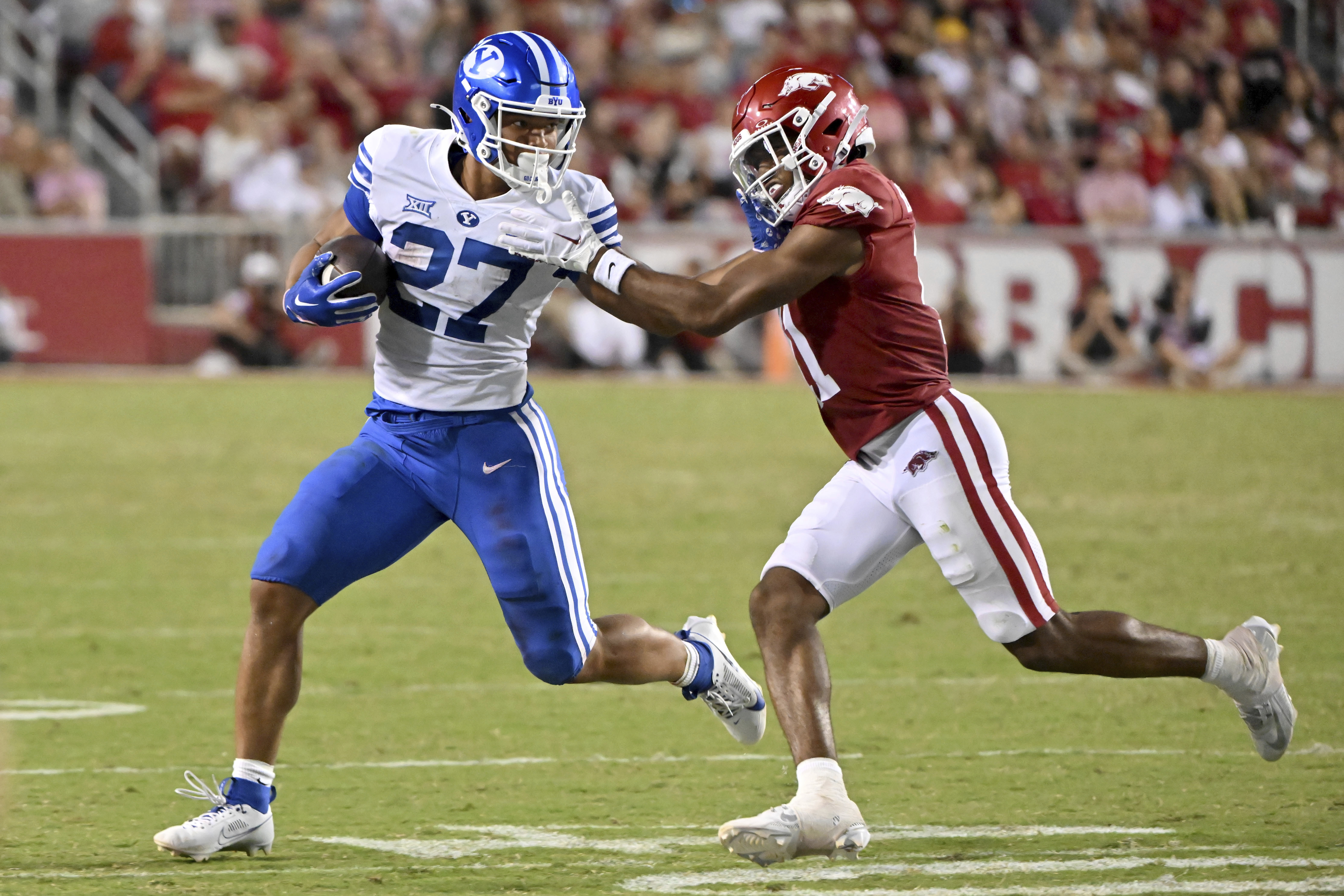FILE - BYU running back LJ Martin (27) tries to get past Arkansas defensive back Jaylon Braxton (11) during an NCAA college football game, Sept. 16, 2023, in Fayetteville, Ark.