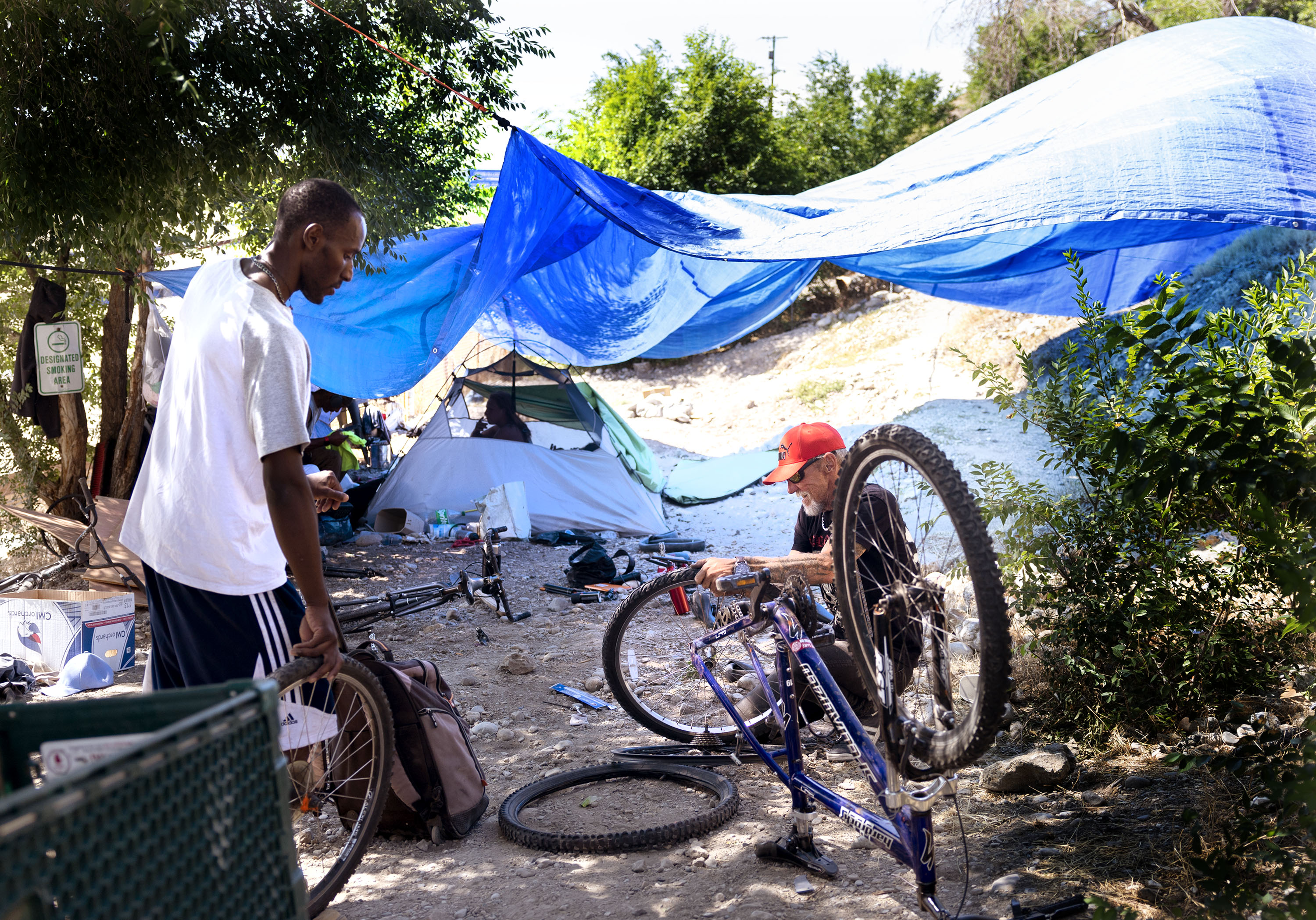 Gucci and Tennessee repair bicycles in a homeless camp in Salt Lake City. The Utah Department of Health and Human Services released the first-ever Utah homeless mortality report last week. 