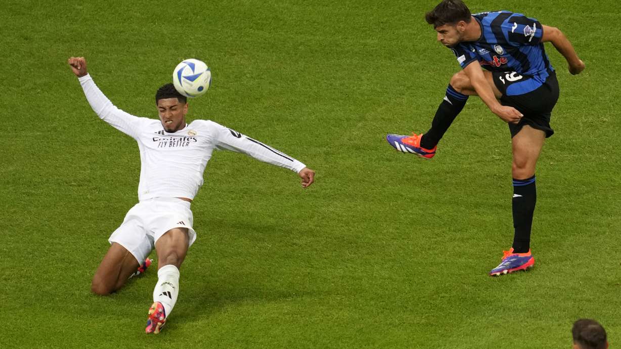 Atalanta's Berat Djimsiti, right, attempts a shot at goal in front of Real Madrid's Jude Bellingham during the UEFA Super Cup Final soccer match between Real Madrid and Atalanta at the Narodowy stadium in Warsaw, Poland, Wednesday, Aug. 14, 2024.
