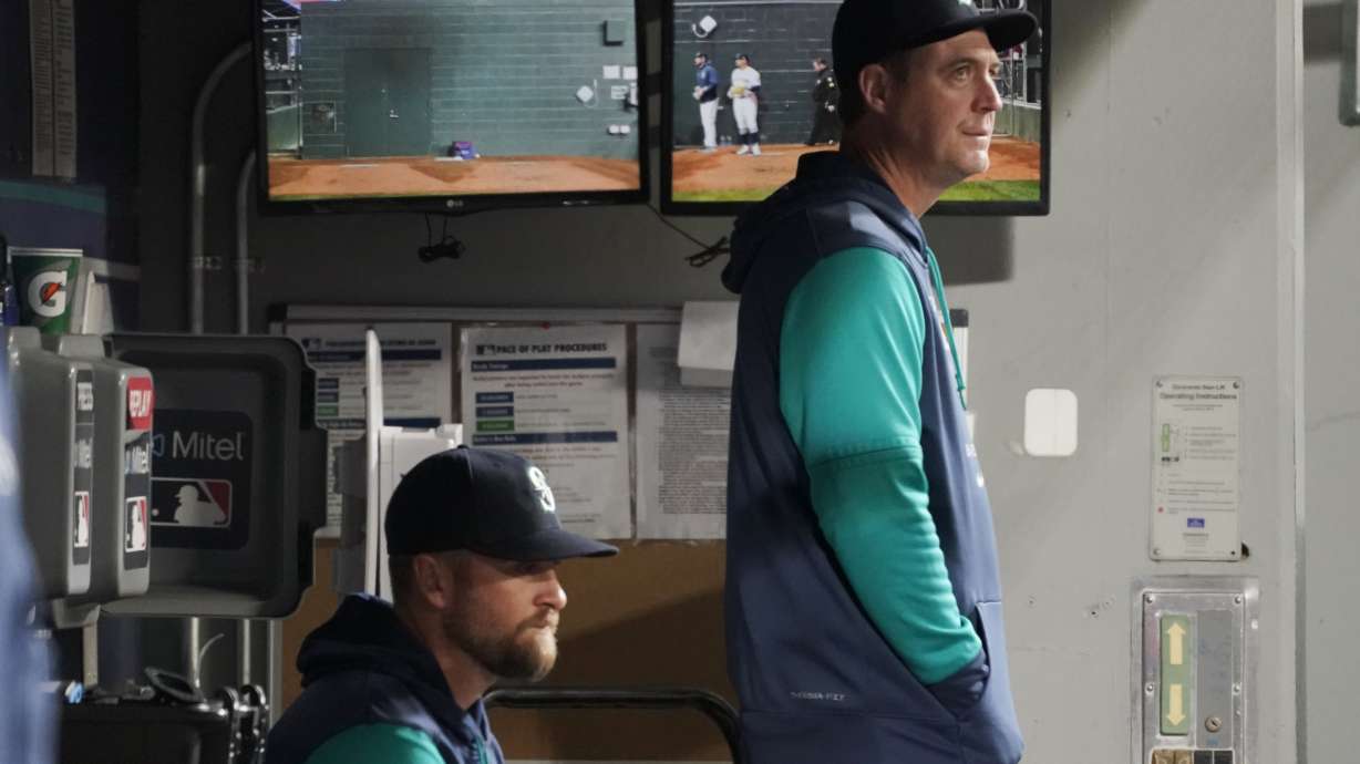 FILE - Seattle Mariners' Dan Wilson, right, stands in the dugout with acting third-base coach Tony Arnerich, left, during a baseball game against the Texas Rangers, Thursday, April 21, 2022, in Seattle.