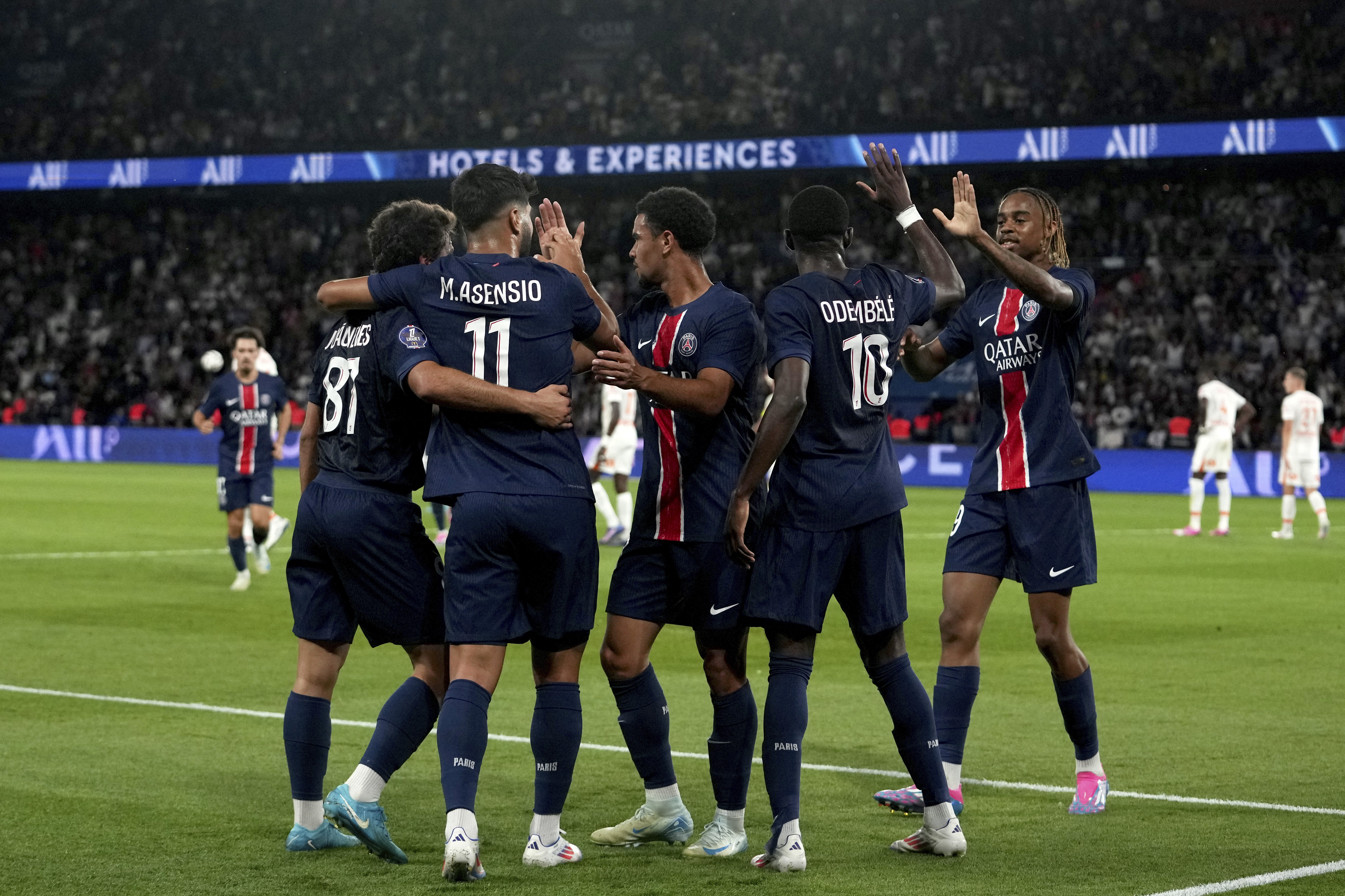 PSG's Marco Asensio, back to camera, celebrates with teammates after scoring his side's second goal during the French League 1 soccer match between Paris Saint-Germain and Montpellier at the Parc des Princes in Paris, Friday, Aug. 23, 2024. 