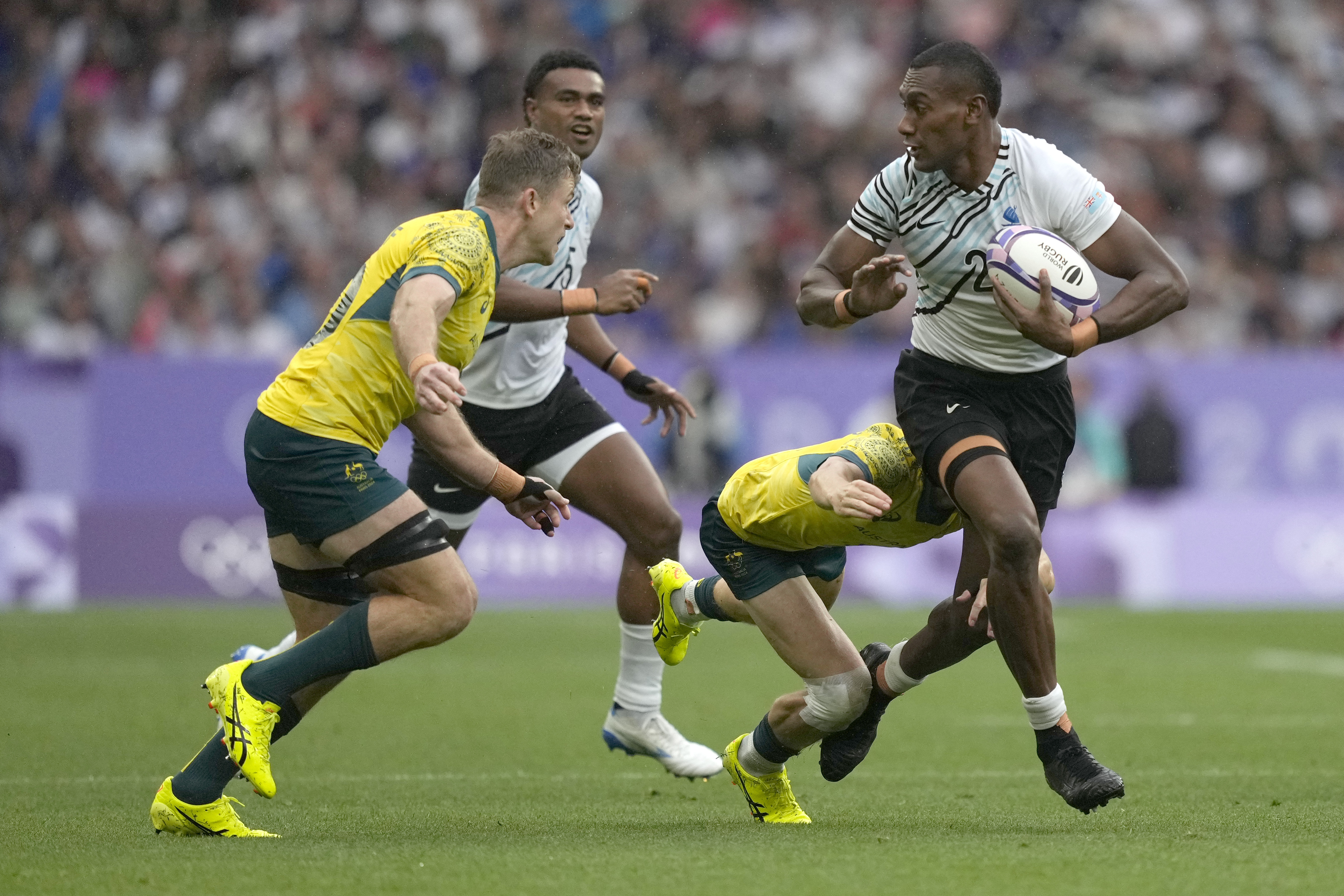 Fiji's Joseva Talacolo, right looks to fend off an incoming tackle form Australia's Nick Malouf left, during the men's semifinal Rugby Sevens match between Fiji and Australia at the 2024 Summer Olympics, in the Stade de France, in Saint-Denis, France, Saturday, July 27, 2024. 