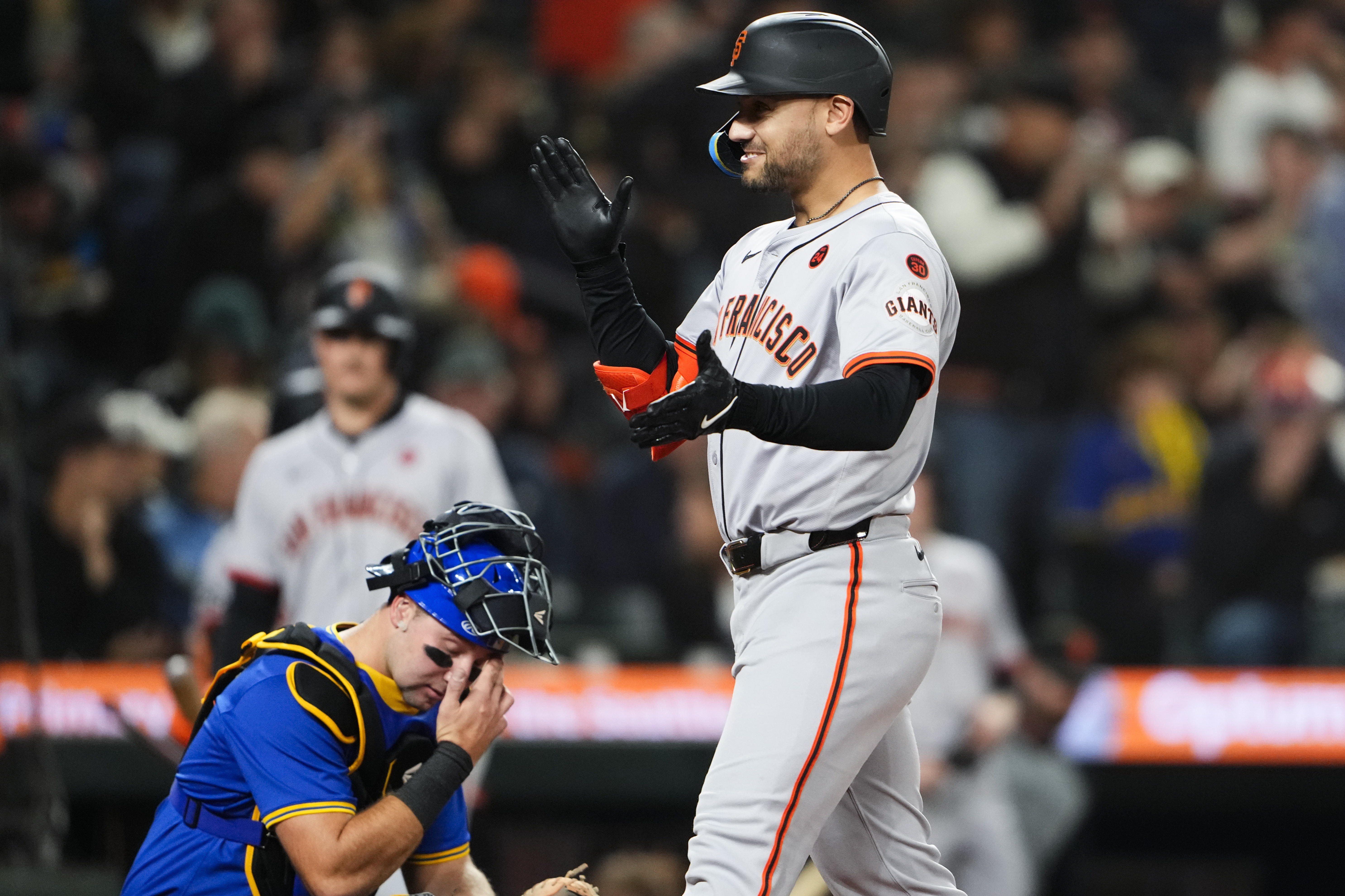 San Francisco Giants' Michael Conforto, right, reacts as he crosses home after hitting a two-run home run as Seattle Mariners catcher Cal Raleigh wipes his eyes during the fourth inning of a baseball game Friday, Aug. 23, 2024, in Seattle. 