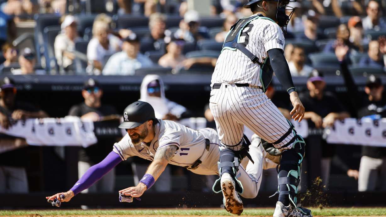 Colorado Rockies' Jake Cave (11) dives to score a run during the third inning of a baseball game against the New York Yankees, Saturday, Aug. 24, 2024, in New York.
