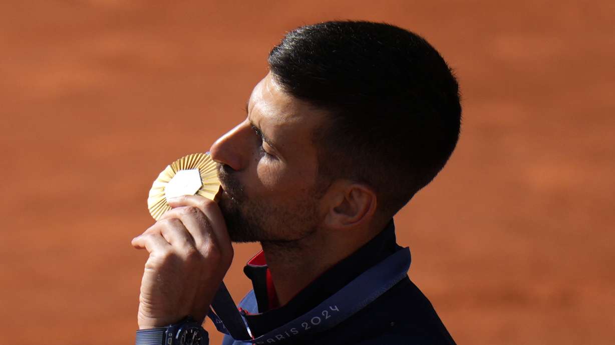 Serbia's Novak Djokovic kisses his gold medal after defeating Spain's Carlos Alcaraz in the men's singles tennis final at the Roland Garros stadium during the 2024 Summer Olympics, Sunday, Aug. 4, 2024, in Paris, France. Djokovic has won his first Olympic gold medal by beating Alcaraz 7-6 (3), 7-6 (2) in the 2024 Games men's tennis singles final.