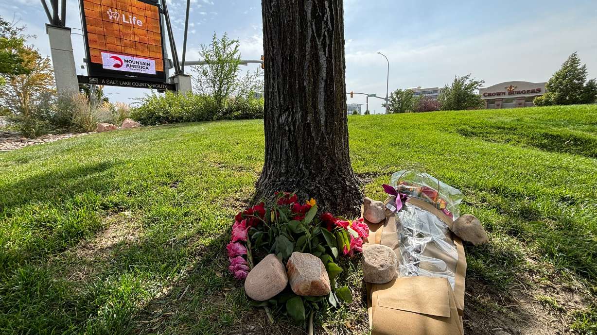 Flowers are placed on Saturday in the area where a high school student died after being stabbed in a parking lot on State Street. Police say a juvenile has been taken into custody.