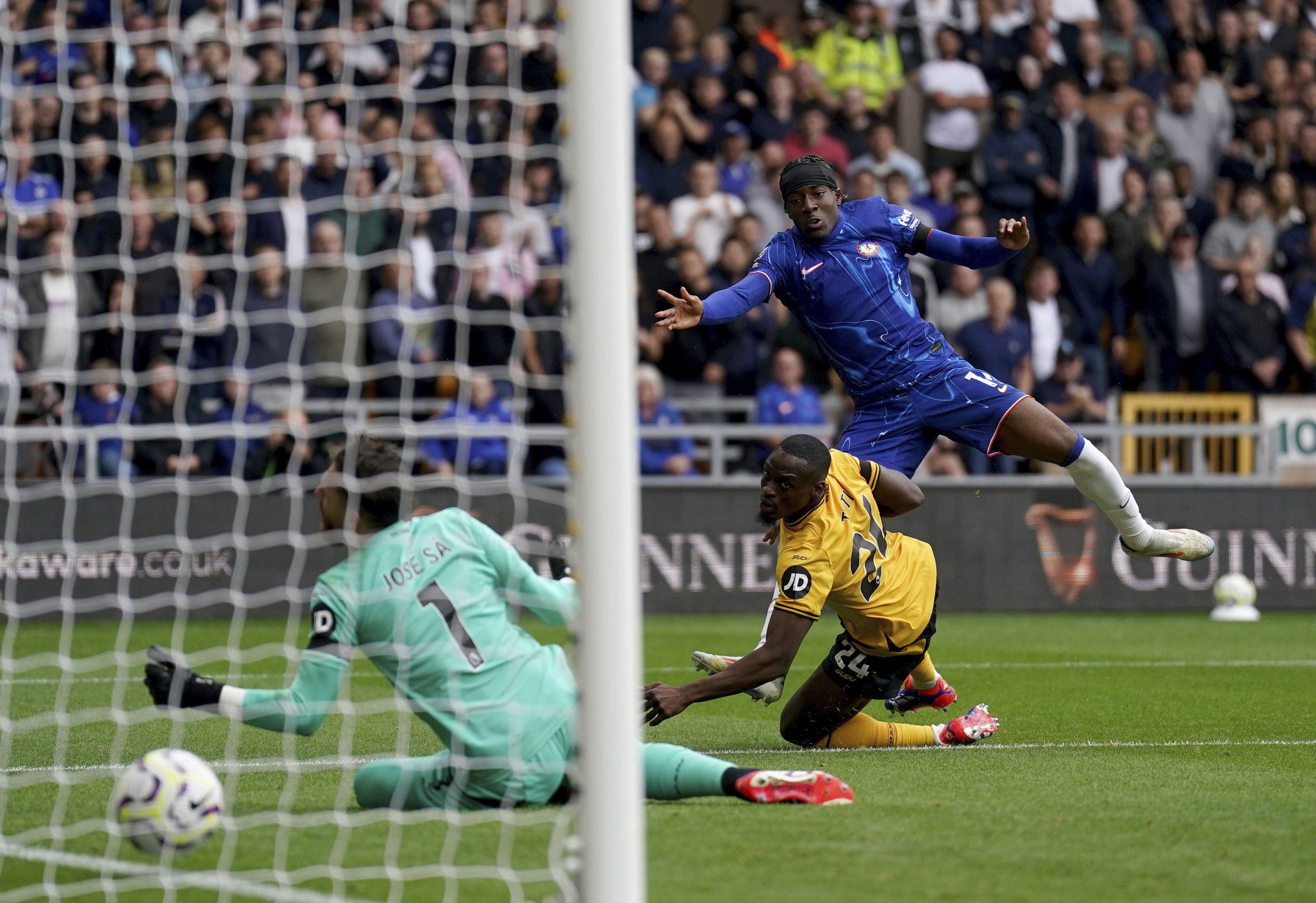 Chelsea's Noni Madueke, top, scores during the English Premier League soccer match between Wolverhampton Wanderers and Chelsea at Molineux Stadium, Wolverhampton, England. Sunday Aug. 25, 2024. 