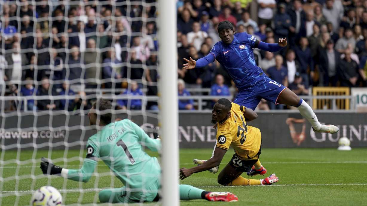 Chelsea's Noni Madueke, top, scores during the English Premier League soccer match between Wolverhampton Wanderers and Chelsea at Molineux Stadium, Wolverhampton, England. Sunday Aug. 25, 2024.