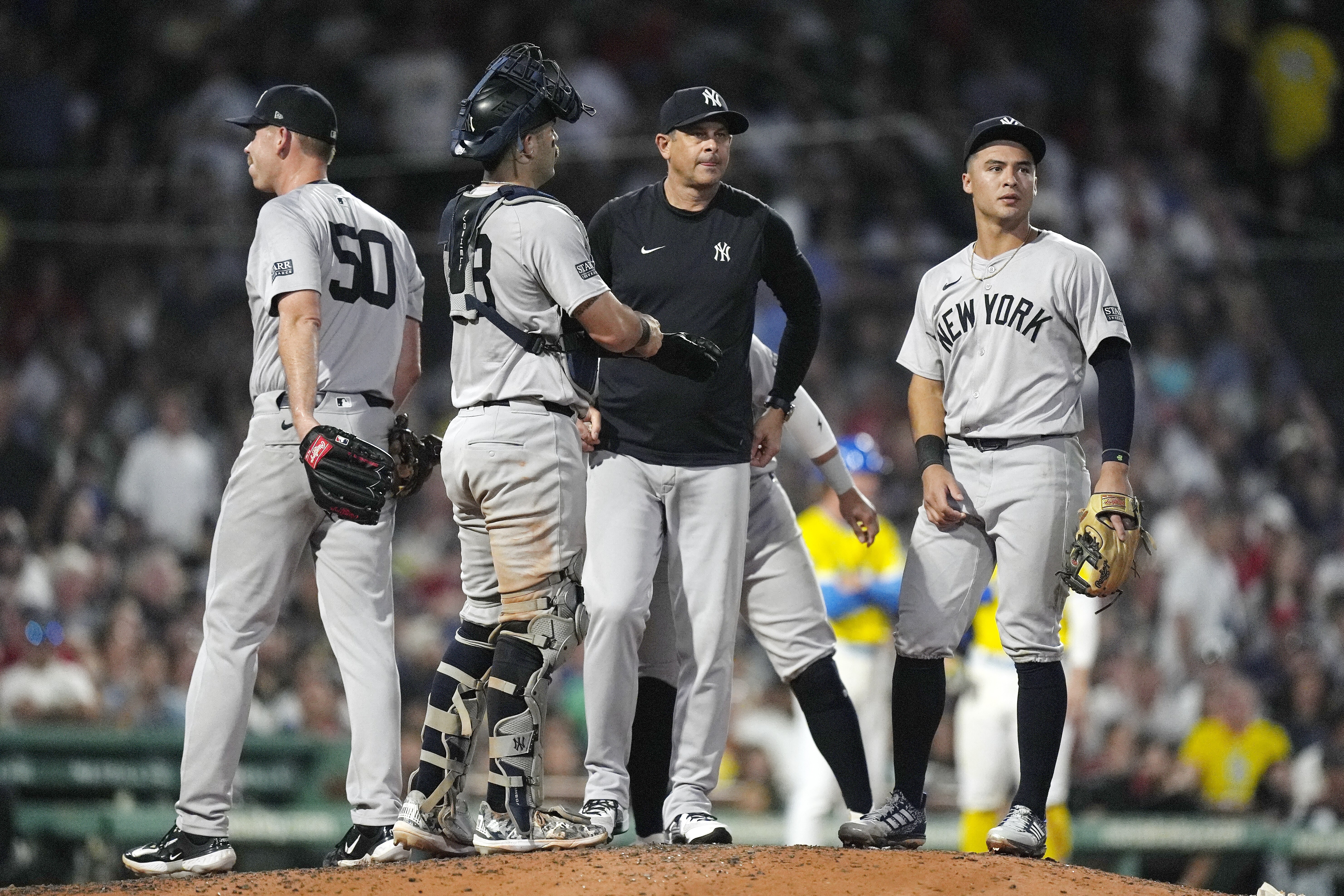 New York Yankees manager Aaron Boone, center right, stands on the mound after relieving Michael Tonkin (50) during the seventh inning of a baseball game against the Boston Red Sox, Saturday, July 27, 2024, in Boston. 