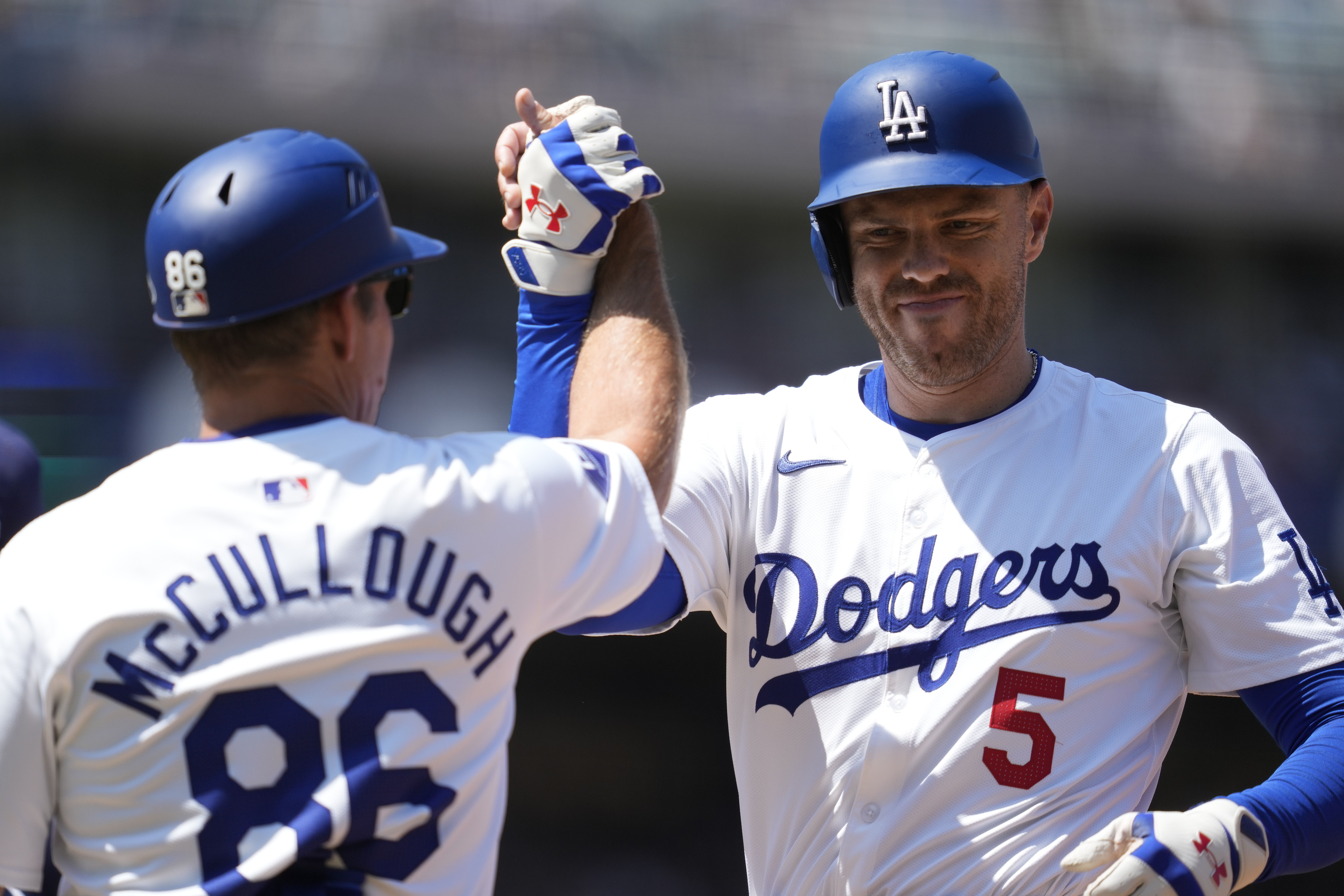 Los Angeles Dodgers' Freddie Freeman (5) celebrates with first base coach Clayton McCullough (86) after a single during the fourth inning of a baseball game against the Tampa Bay Rays in Los Angeles, Sunday, Aug. 25, 2024.